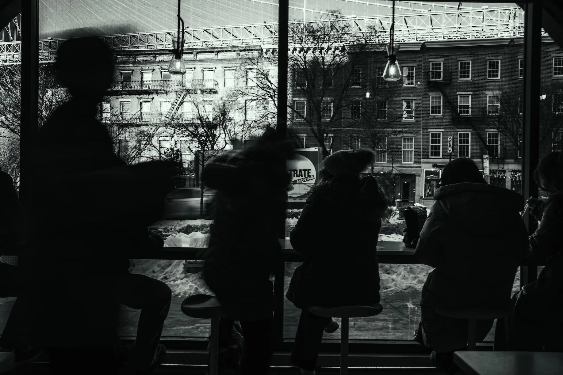 artistic black and white image of people sitting in a cafe looking out the window
