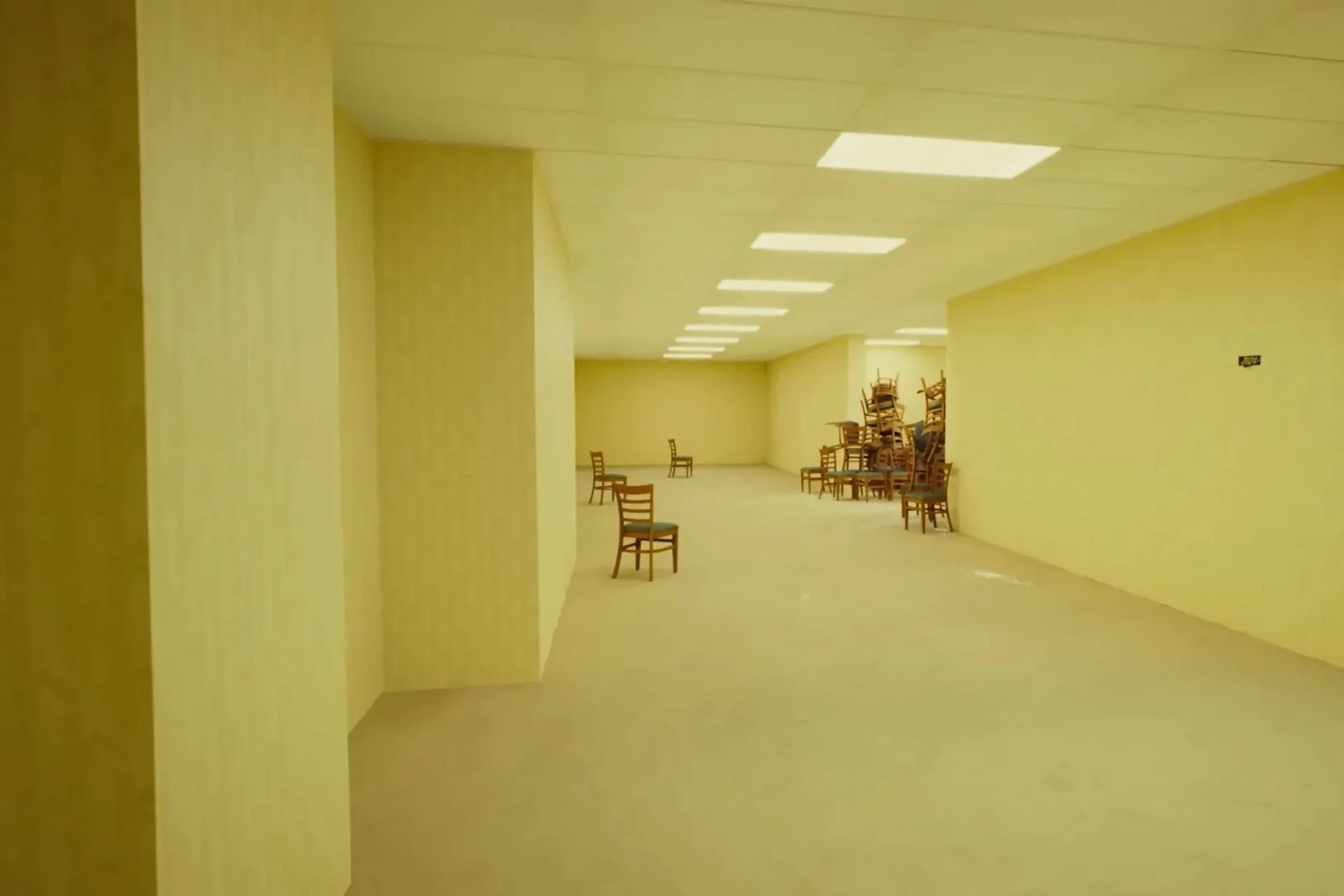 still shot from the movie "Backrooms" with yellow walls and stacked chairs