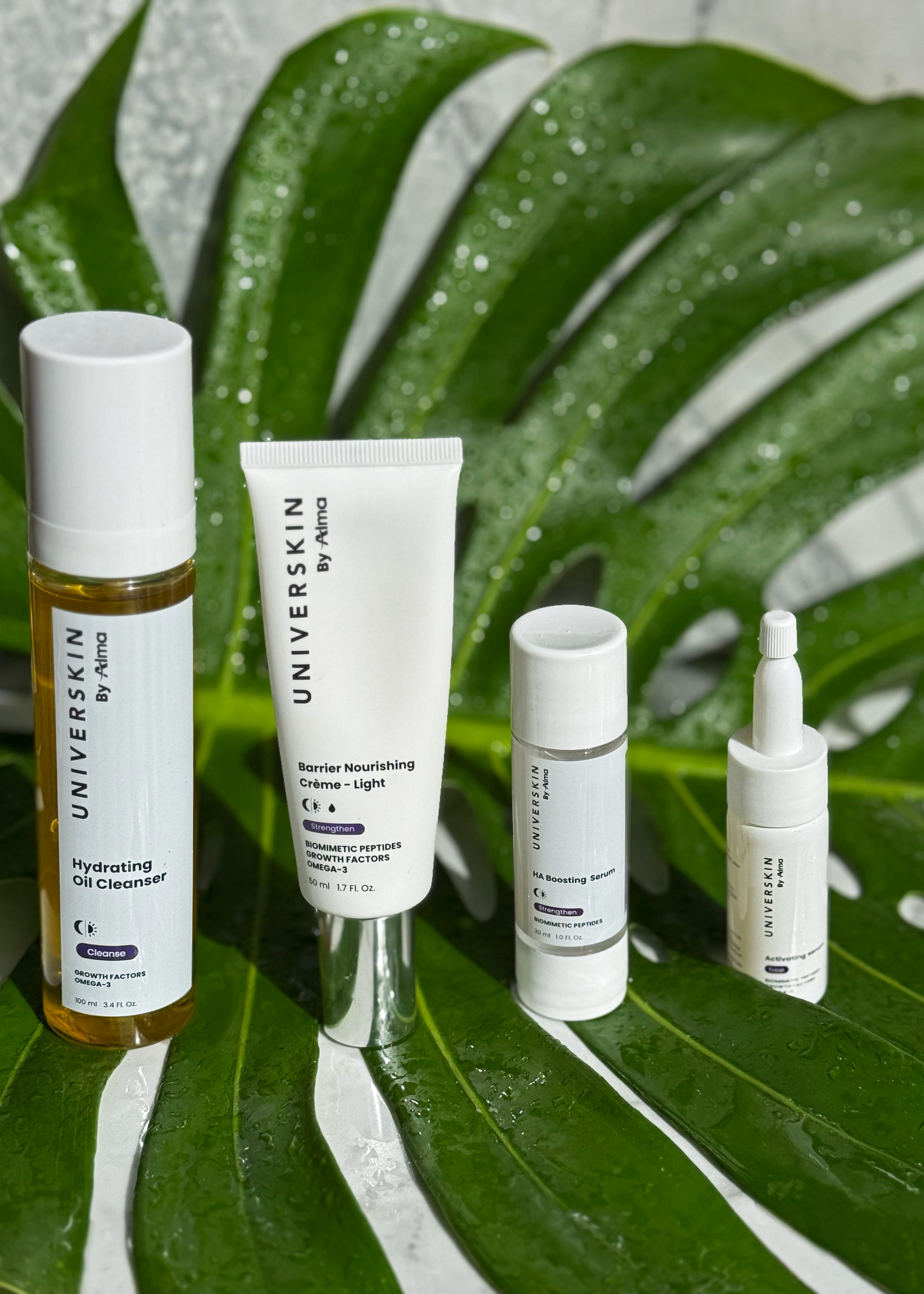IMAGE OF NEW SKINCARE LINE, UNIVERSKIN. SHOWN ARE FOUR PIECES, THE OIL CLEANSER, BARRIER NOURISHING CREME, HYLAURONIC ACID SERUM, AND CUSTOM MIXED SERUM.
