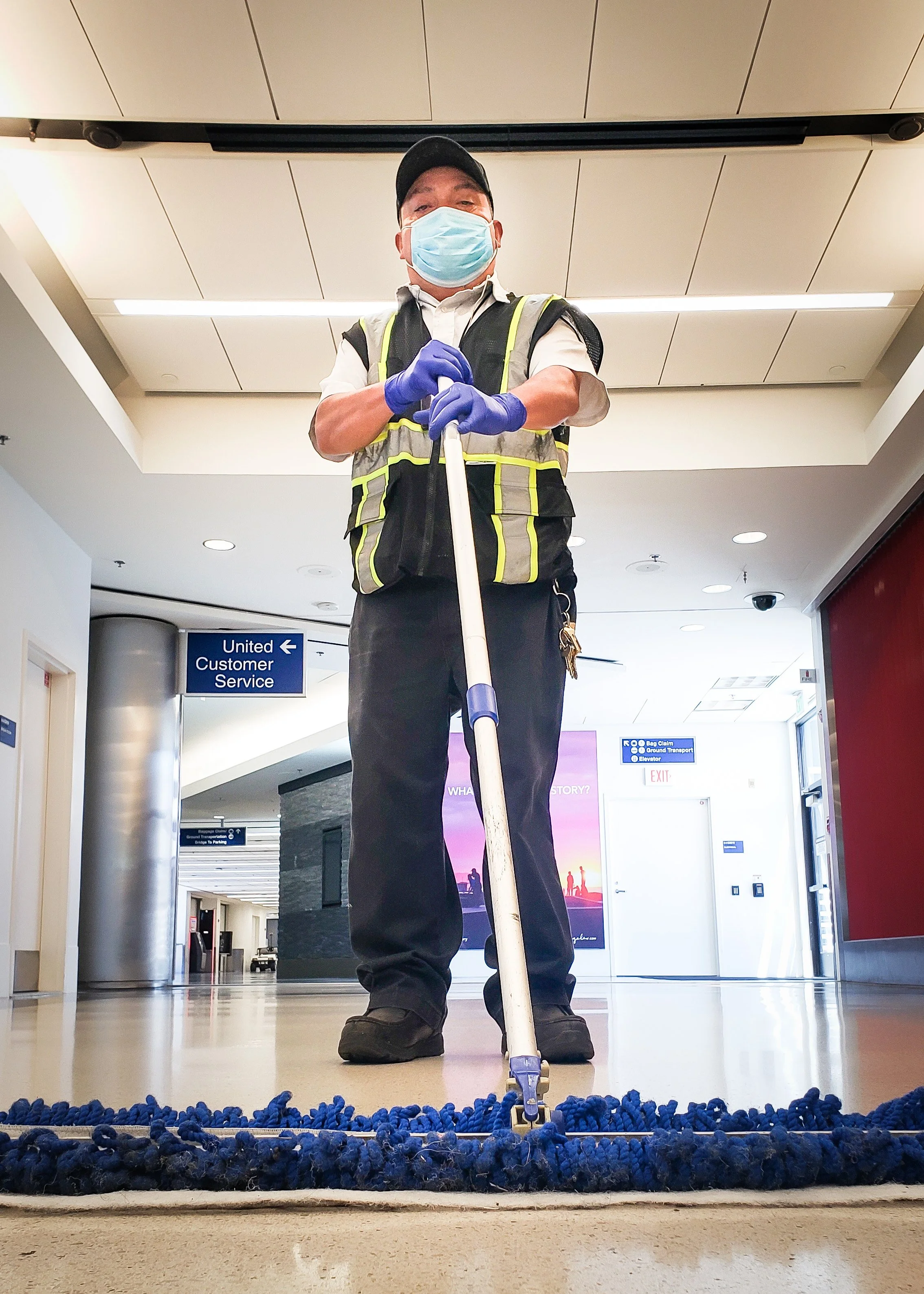An airport employee wearing a face mask and gloves