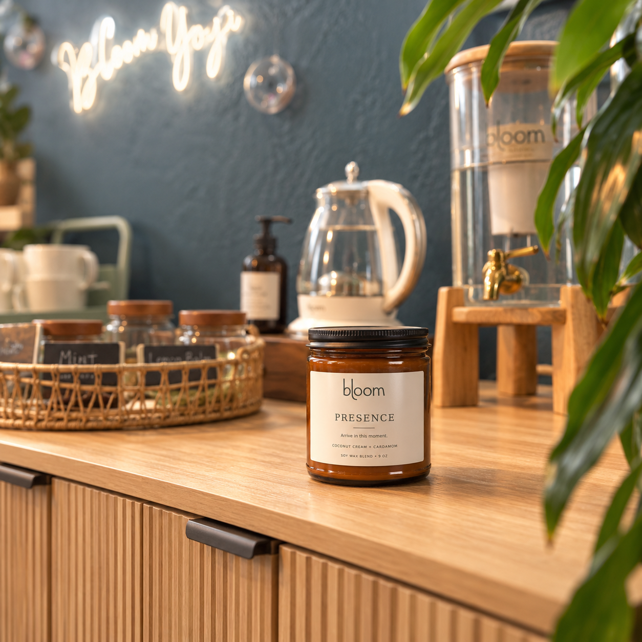 Bloom Presence 9 oz Coconut Cream and Cardamom candle on the tea station at Bloom Yoga; styled product mockup.
