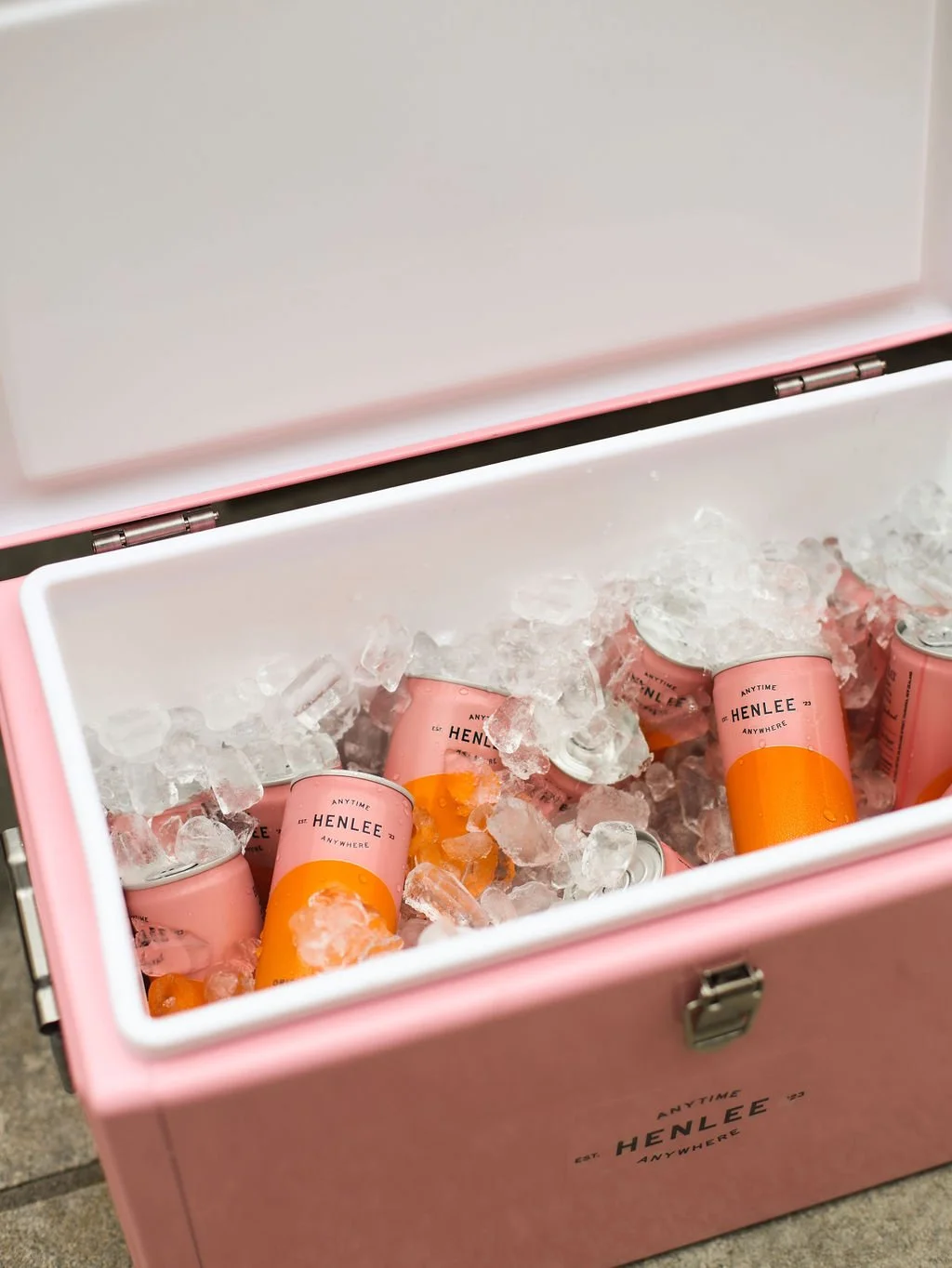 Pink cooler filled with ice and cans of Henlee Mimosas.
