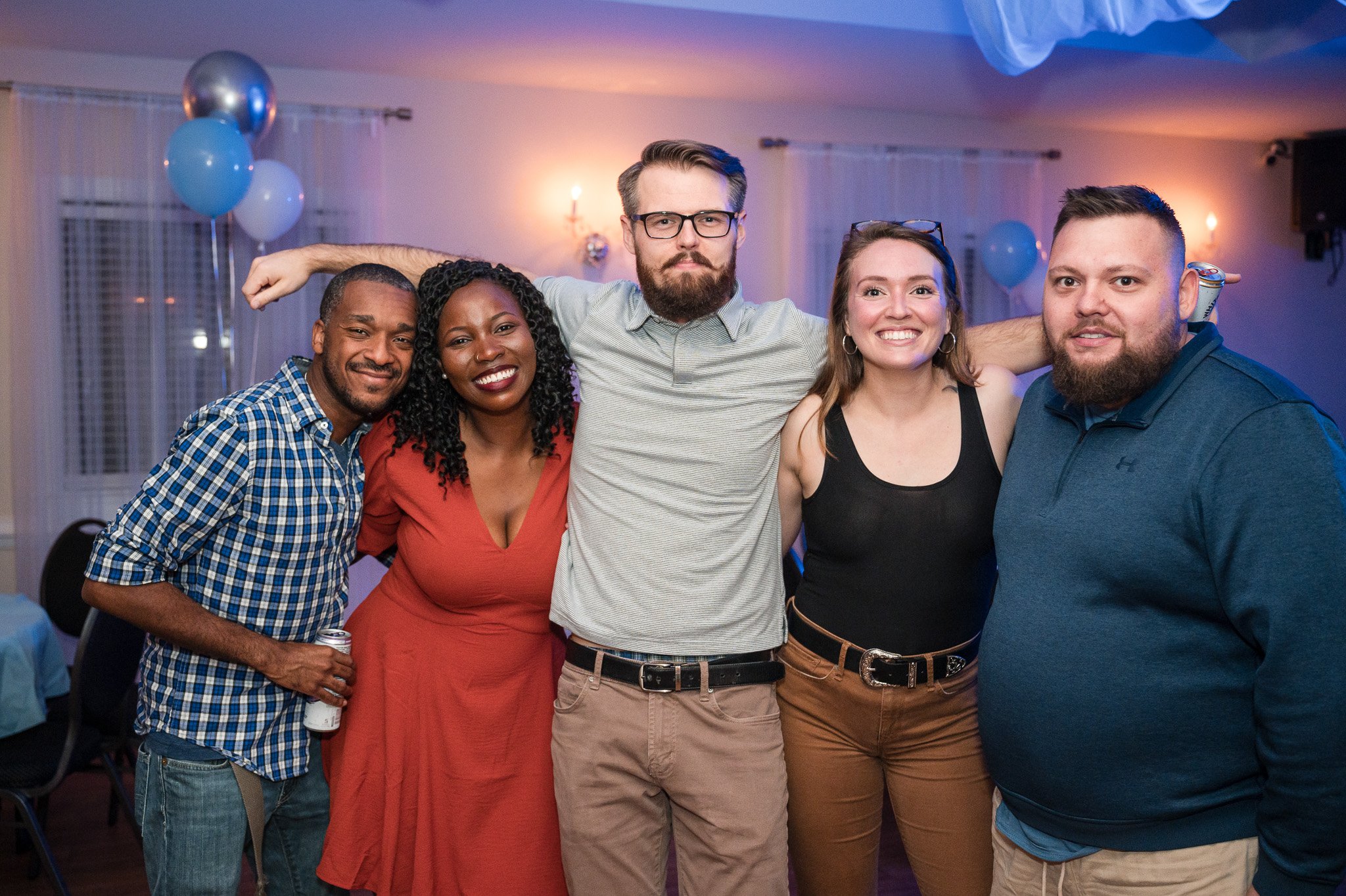 Group of five friends posing together at a party with blue and silver balloons in the background. Clayton event photography