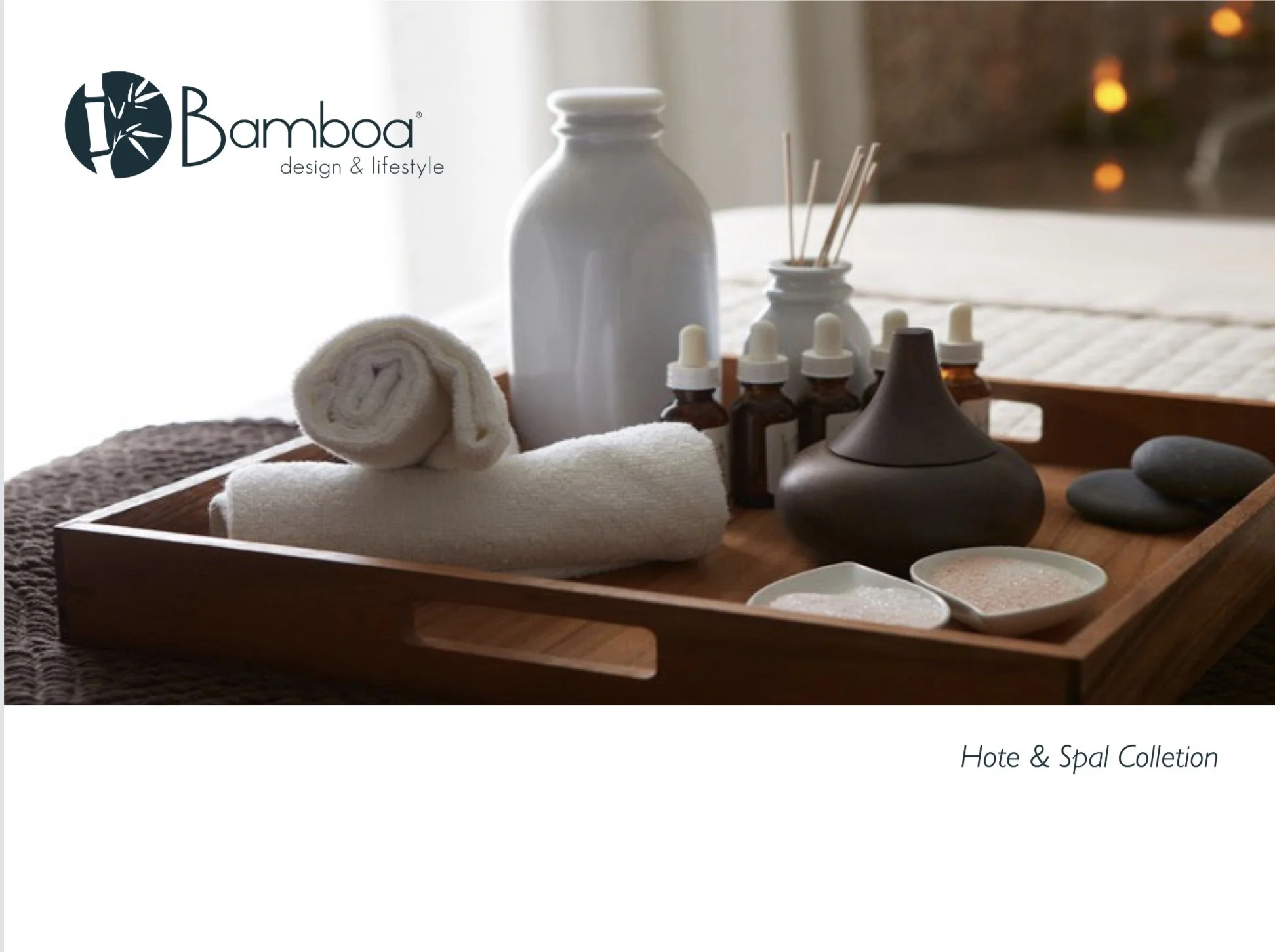 Spa tray with rolled white towels, small bottles with droppers, a dark ceramic vessel, smooth stones, and small bowls of bath salts, with a blurred warm background.
