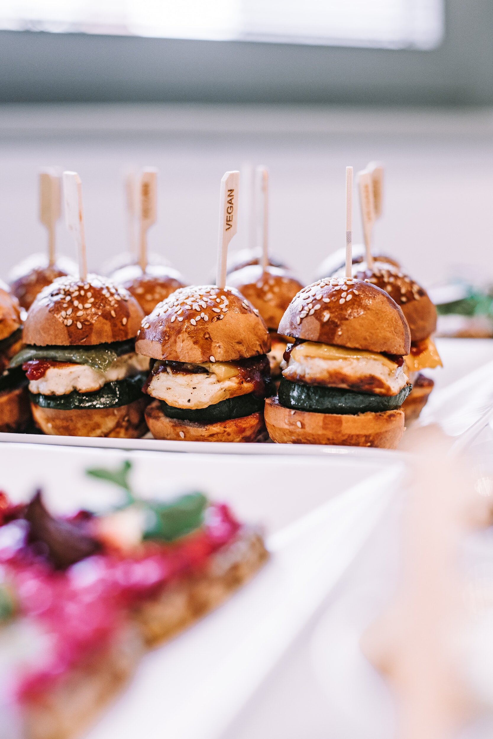 Mini burgers végétaliens avec des petits pains au sésame sur un plateau.