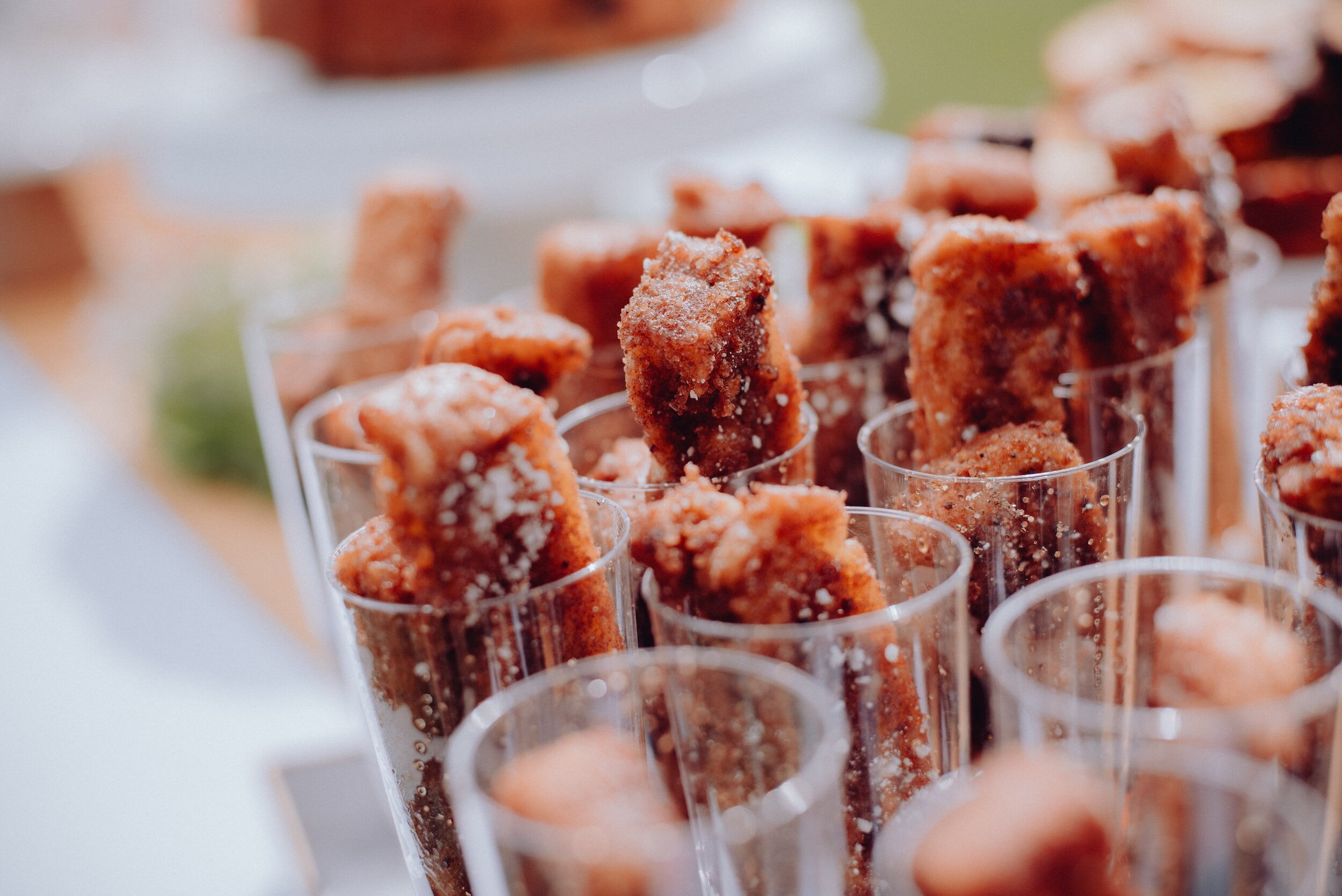 Bouchées de churros saupoudrées de sucre dans des gobelets transparents.