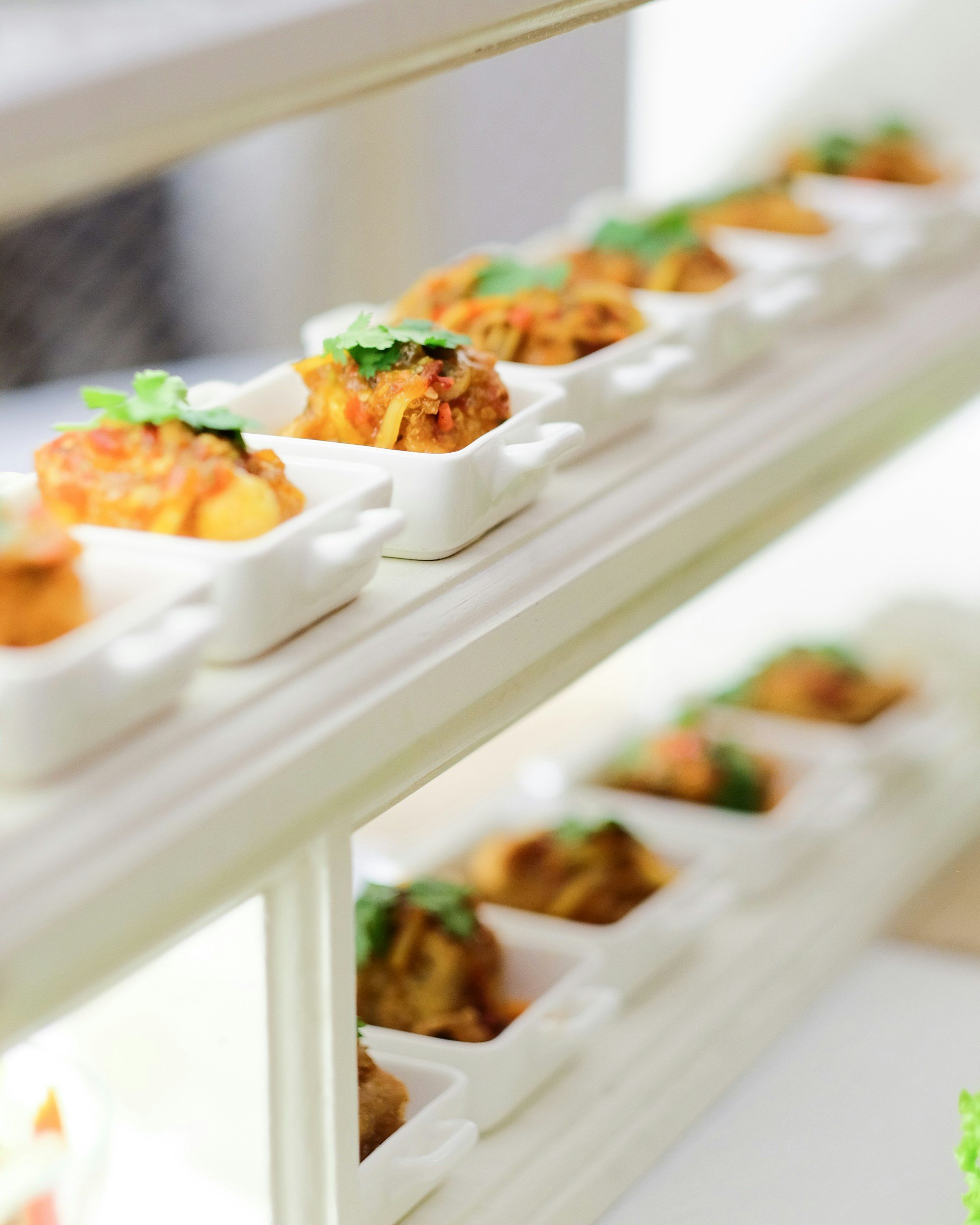 Miniatures de plats de cuisine asiatique, présentées dans de petites assiettes blanches sur un plateau en bois.