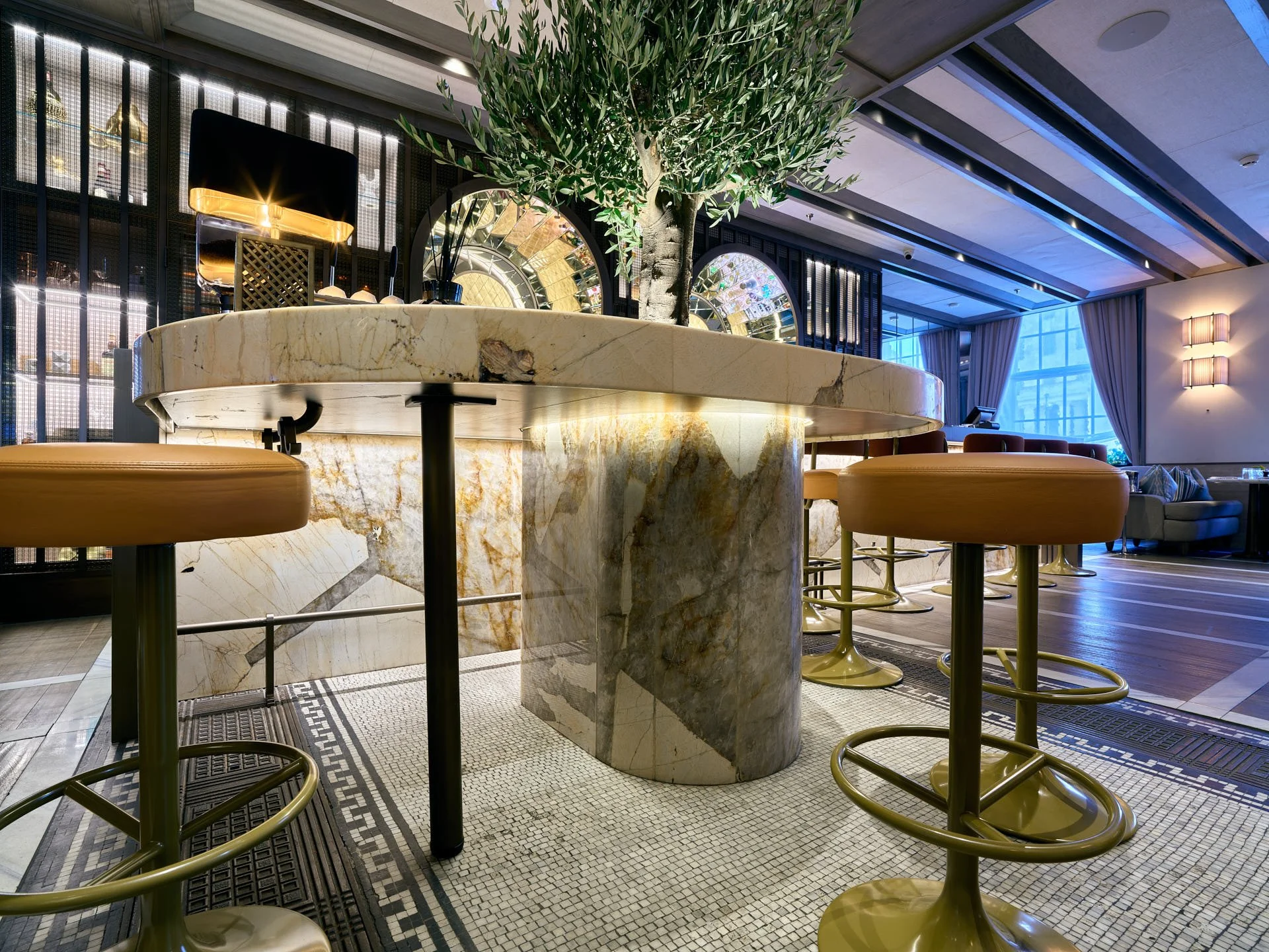 Low-angle view of a thick curved stone tabletop and cylindrical stone leg beside the illuminated bar.