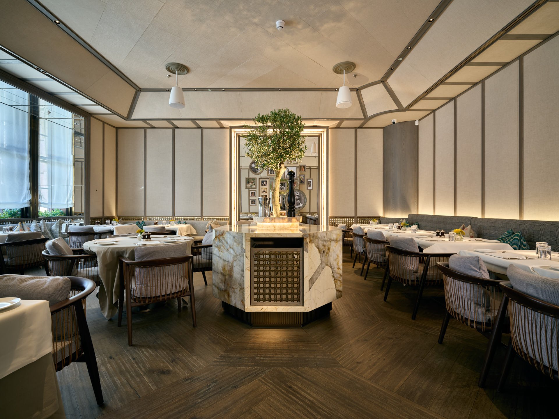 Symmetrical dining room with an octagonal stone cabinet and olive tree at its centre.
