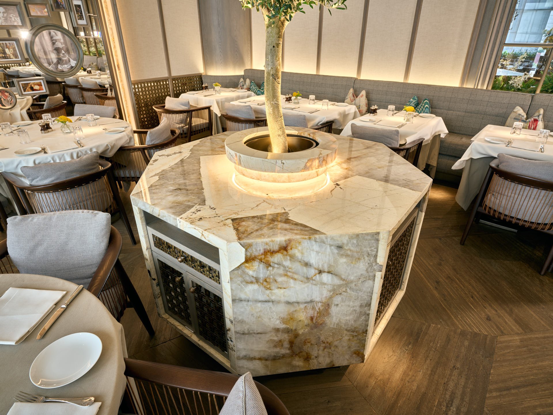 Angled overhead view of an octagonal stone dining table with a circular centre and olive tree.