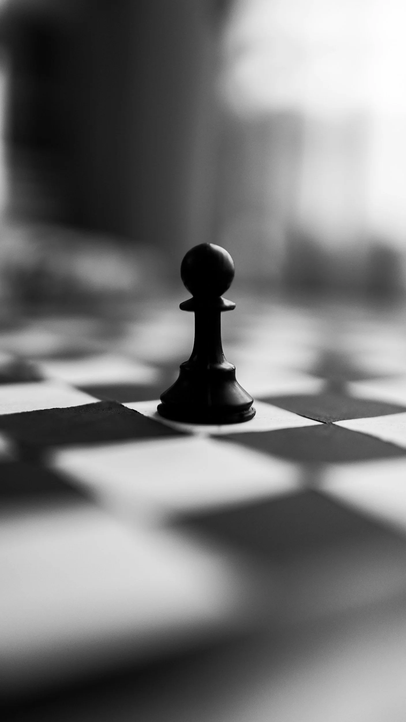 Black pawn chess piece on a checkerboard in black and white
