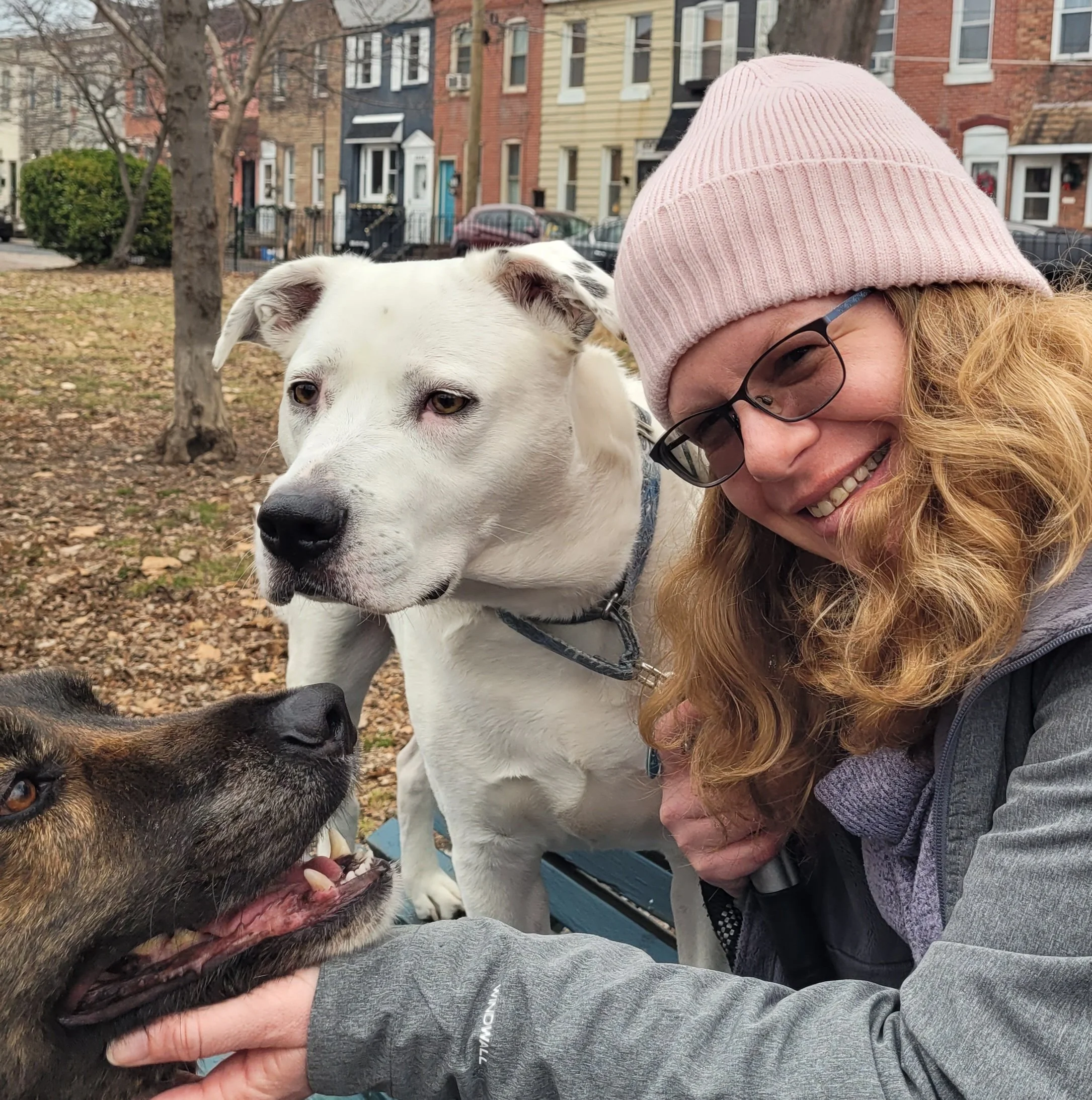 Joanna Nichols, LCSW, smiling outdoors with her two rescue dogs.