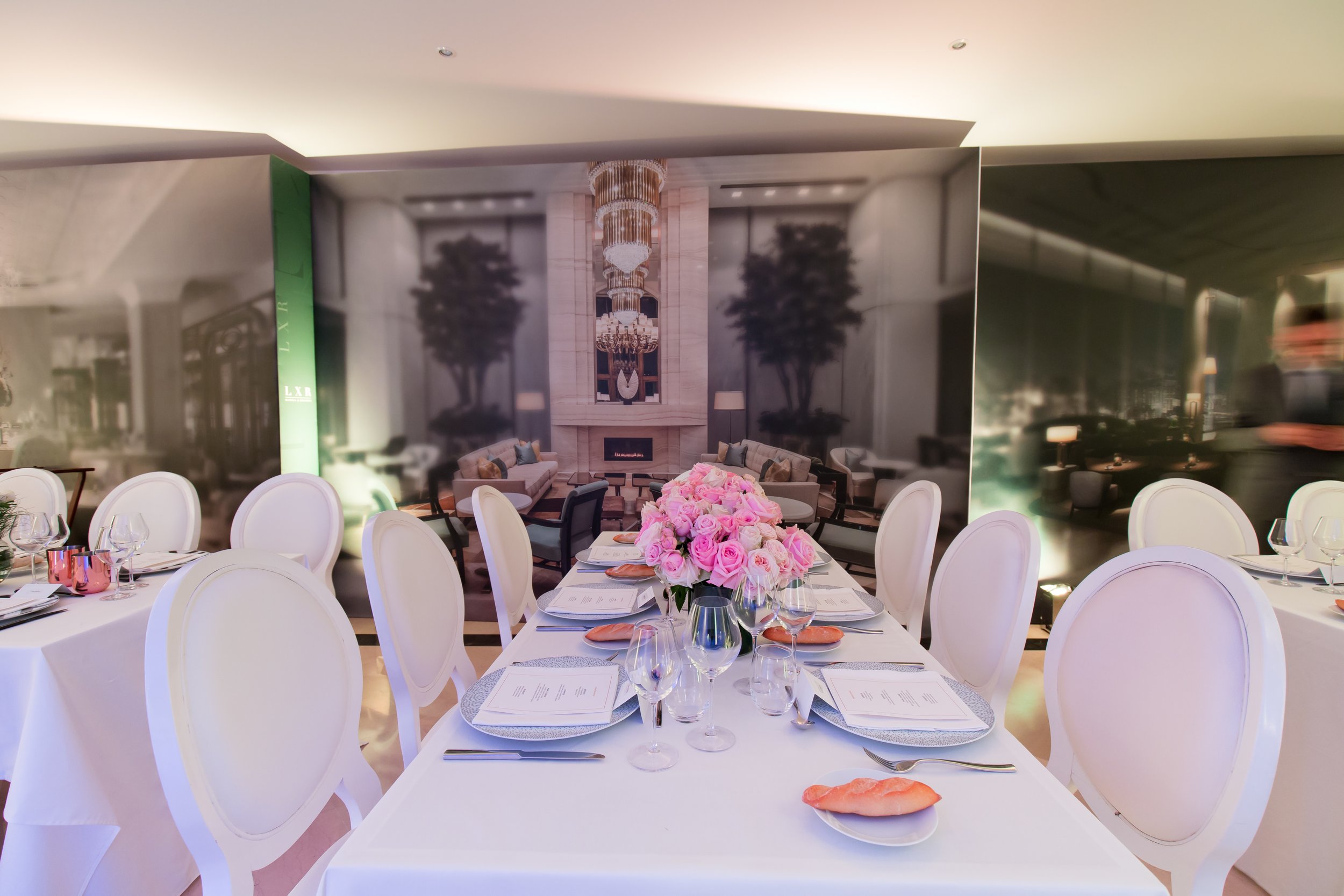 Waldorf Astoria ILTM Cannes — grand lounge space with tall palms, elegant neutral furniture and branded backdrop, designed by Tiny Penthouse Studio