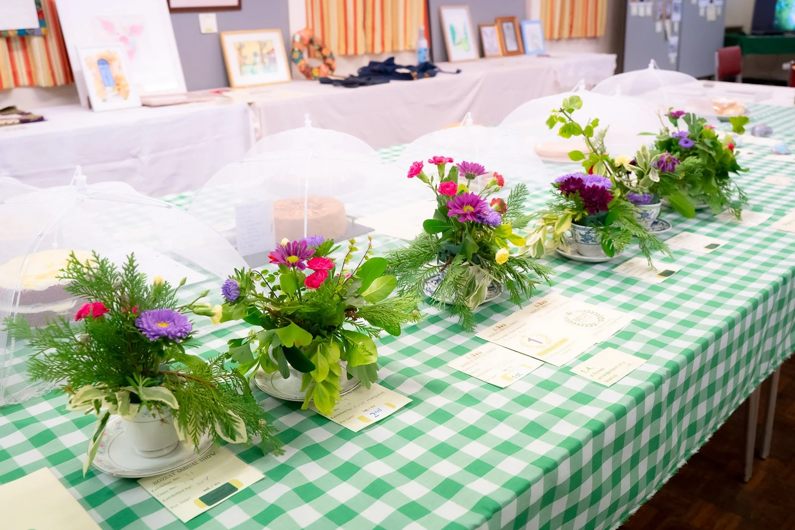 Teacup flower display on green gingham tablecloth