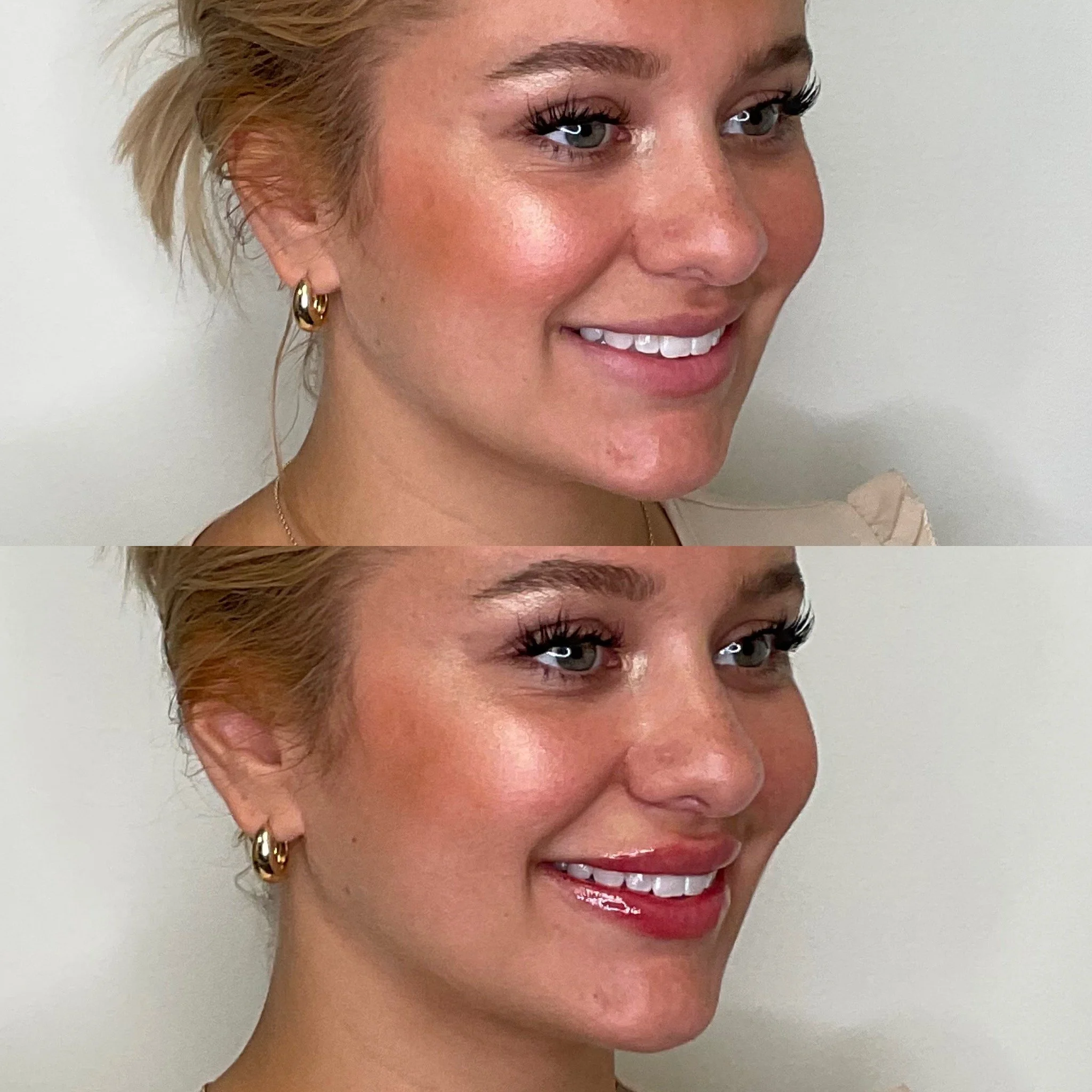A close-up of a smiling woman with short blonde hair, wearing gold hoop earrings, red lipstick, and a necklace, standing against a plain light-colored background.