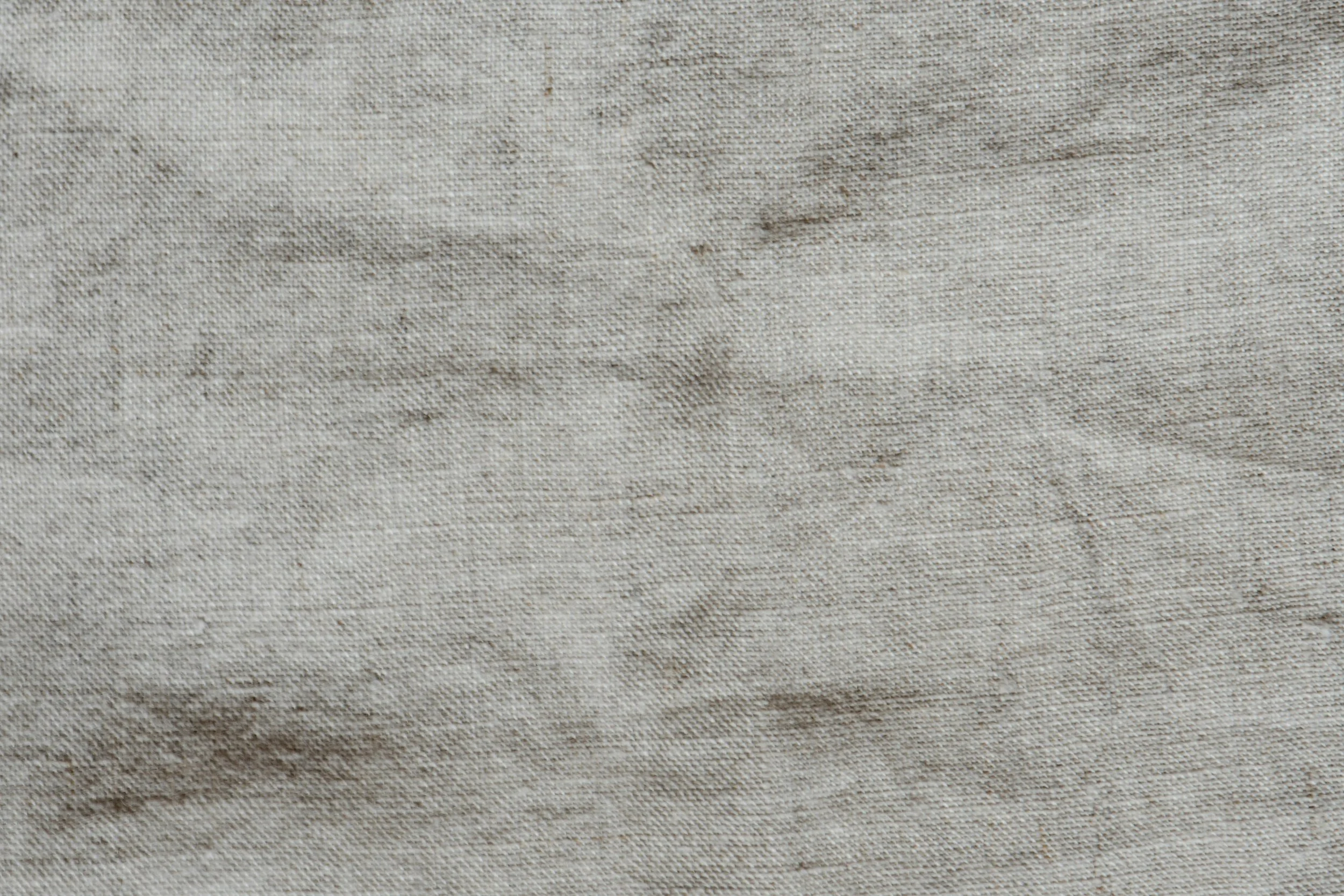 Close-up of beige fabric texture with subtle fibers and wrinkles