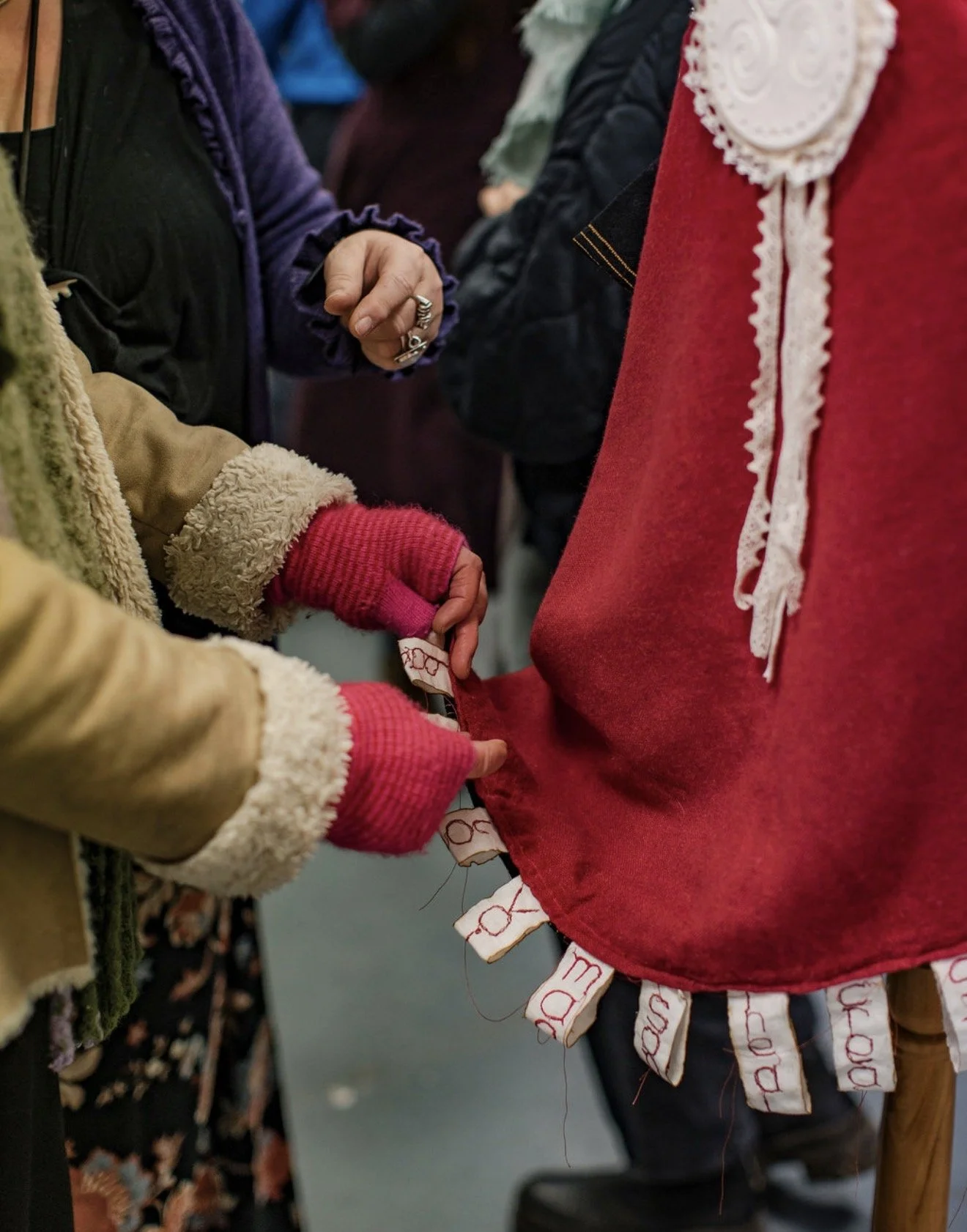 the image shows a shawl at an art show and the hands of two  people examining the materials