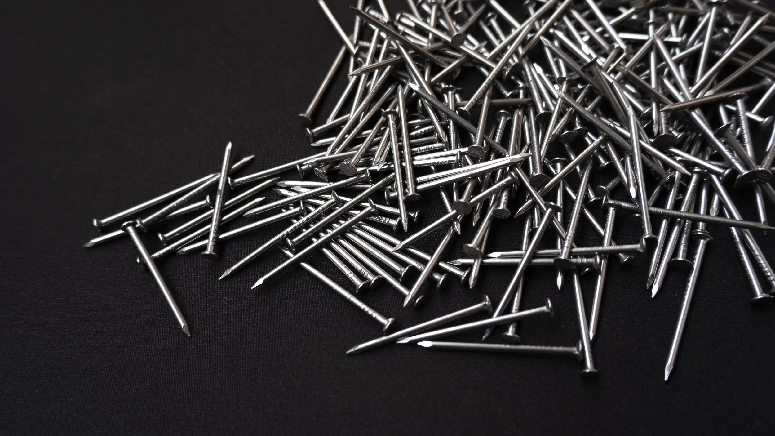 Pile of silver nails on a black surface