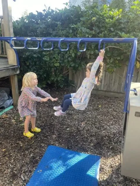 Two girls playing on the swings outside