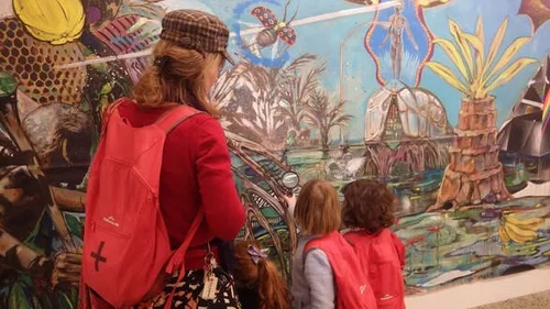 A teacher and two children looking at a colourful jungle mural