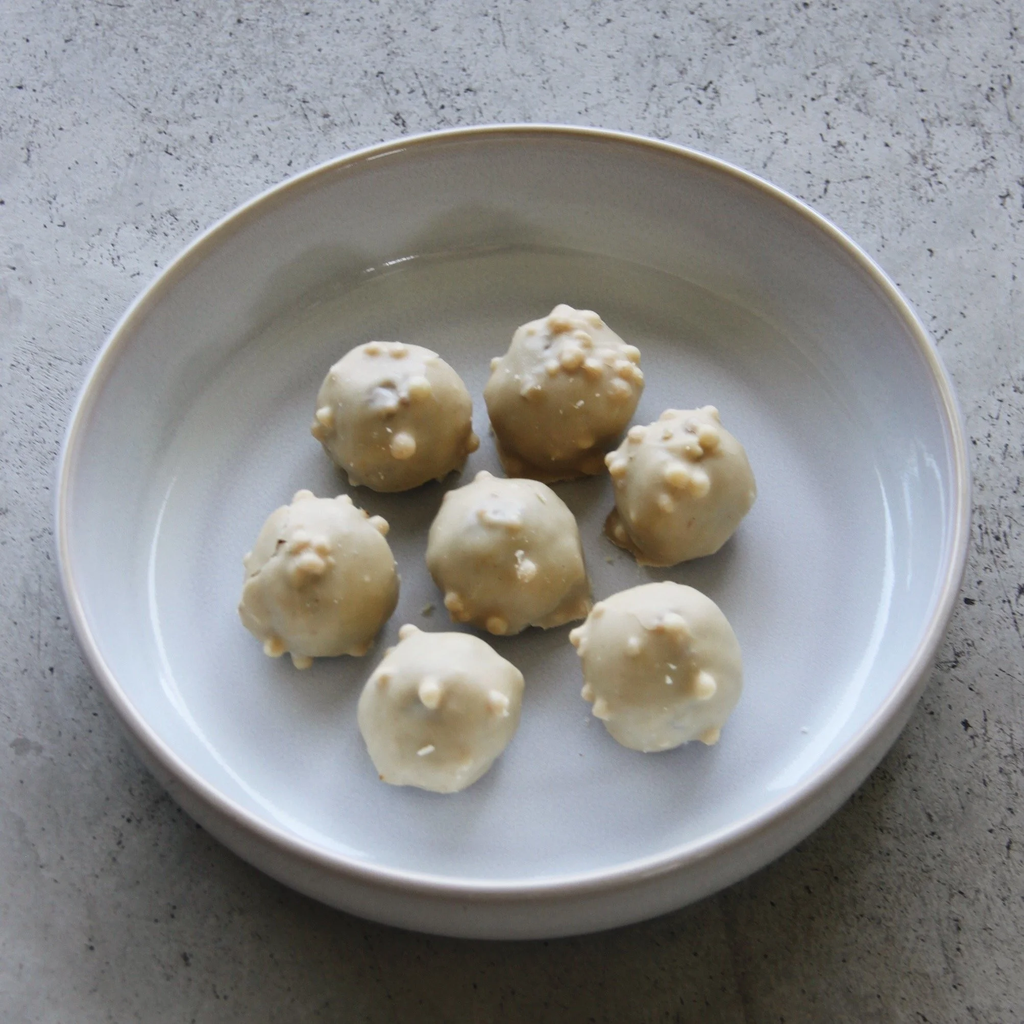 Weiße Schokolade-Trüffel mit Knöpfen auf einer weißen Schale