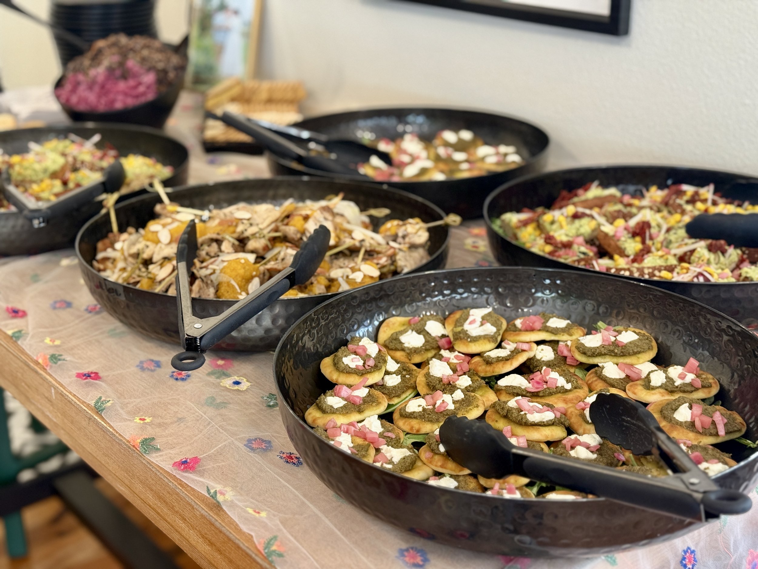 Buffet with various dishes in black bowls, including appetizers and salads.