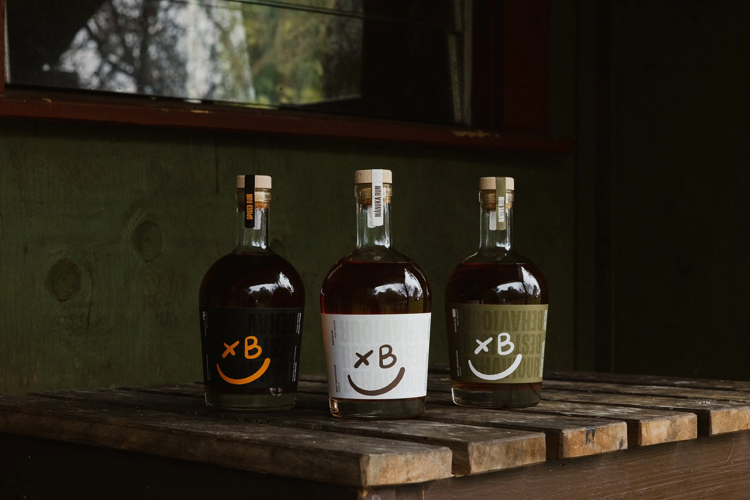 Three bottles of alcohol with smiley face labels on a wooden shelf
