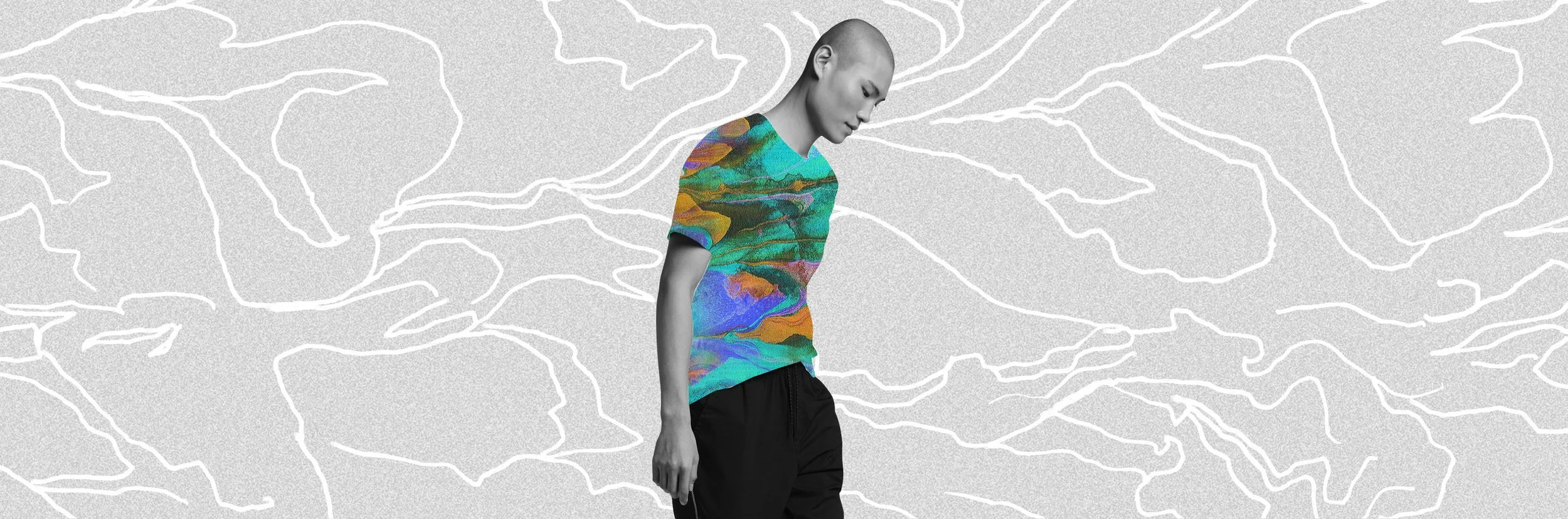 A person with a bald head looking downward, wearing a colorful abstract-patterned t-shirt and black pants, standing against a gray background with white outline of leaves.