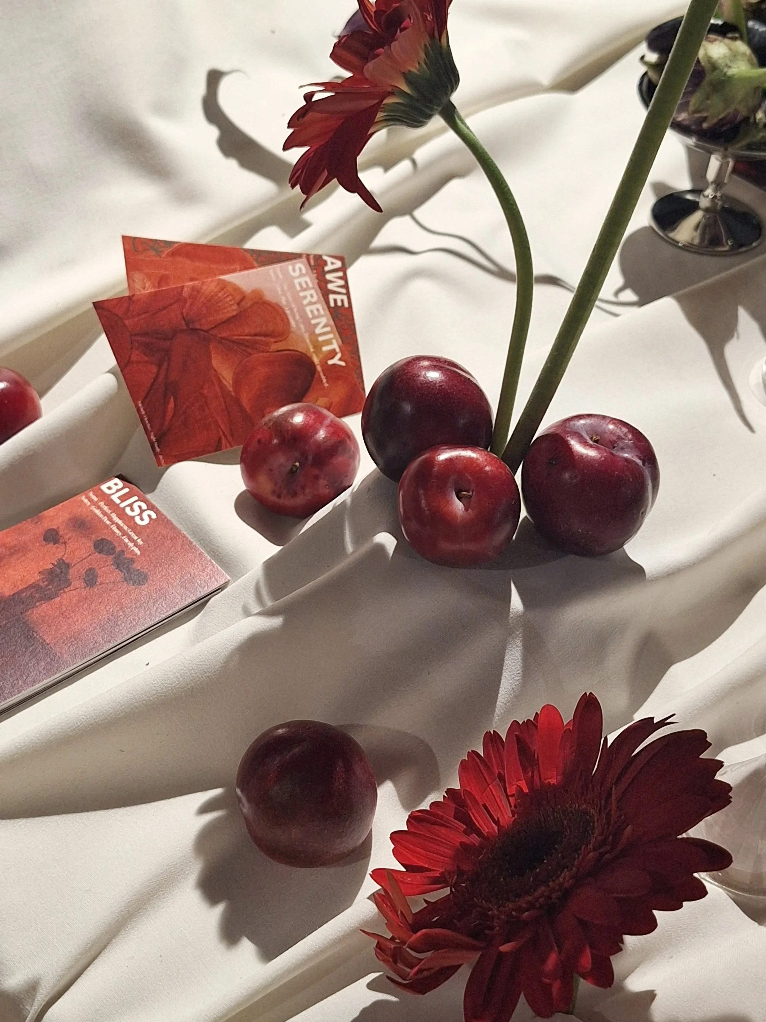 red flowers and fruits are strewn on a sumptuous table showcasing scents created to represent emotions - namely bliss, awe, and serenity