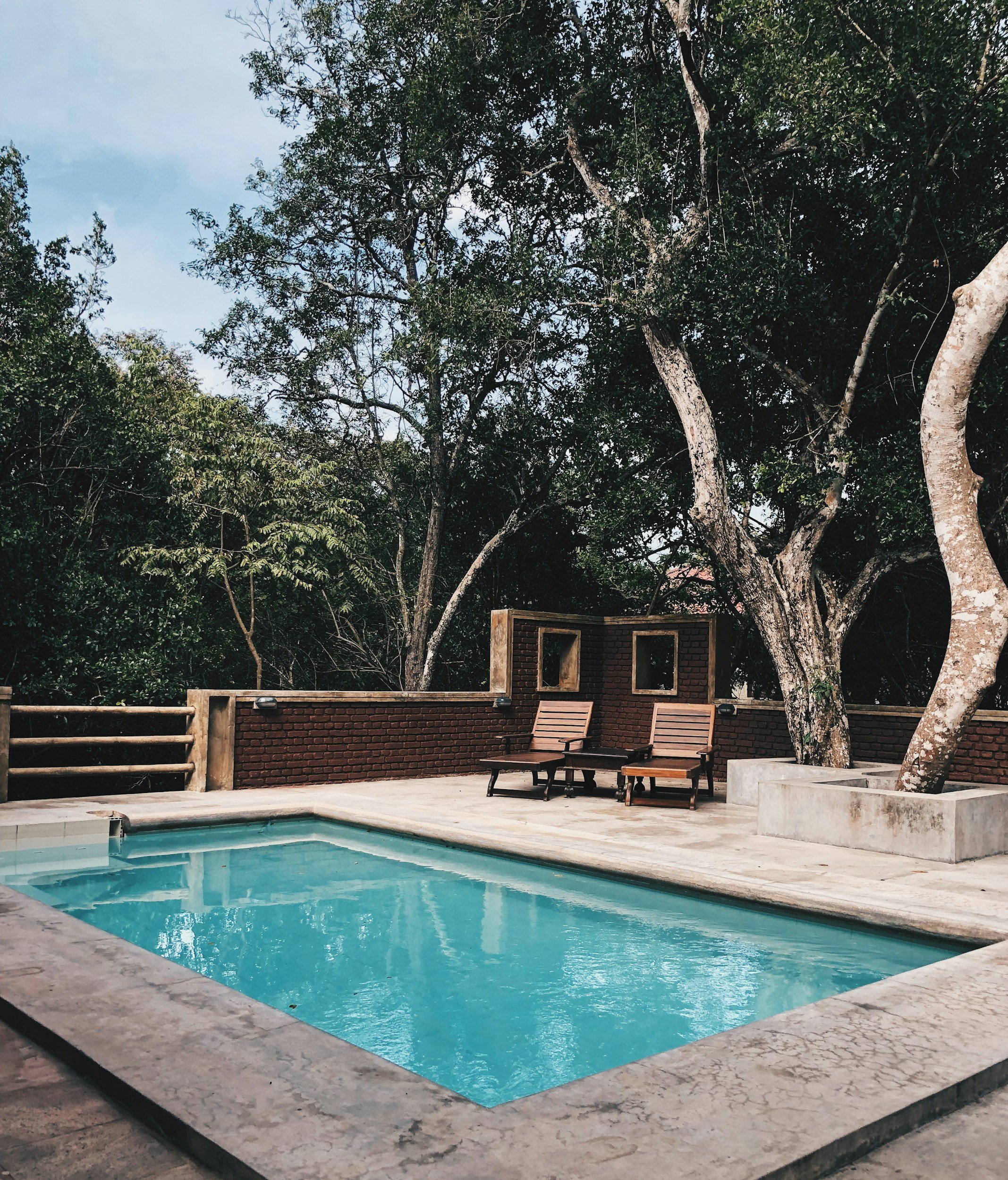 Outdoor swimming pool with surrounding trees and deck chairs