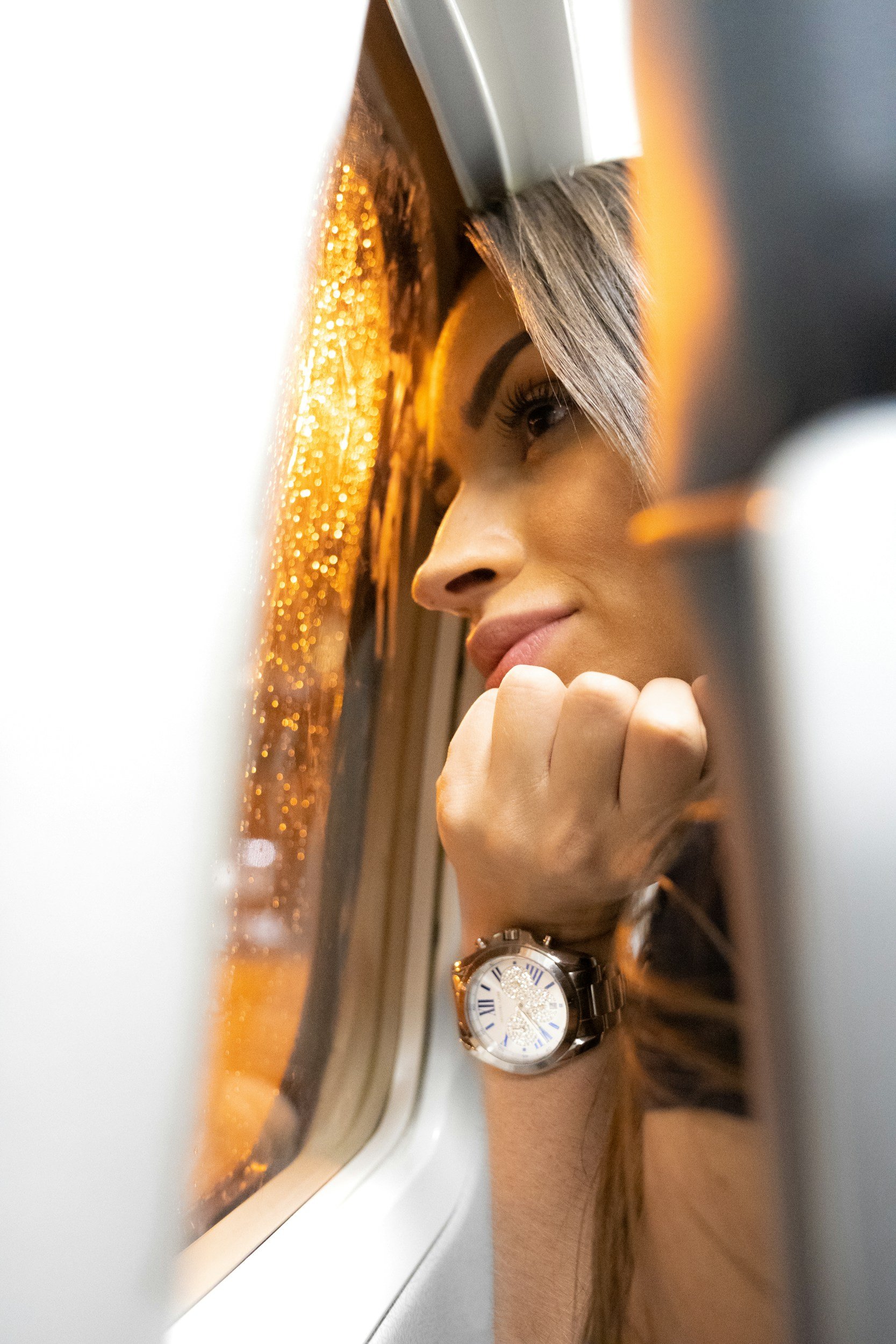 Woman looking out of a plane window with raindrops, wearing a wristwatch. Real Estate Agents Who Help First-Time Buyers Secure Their Dream Home