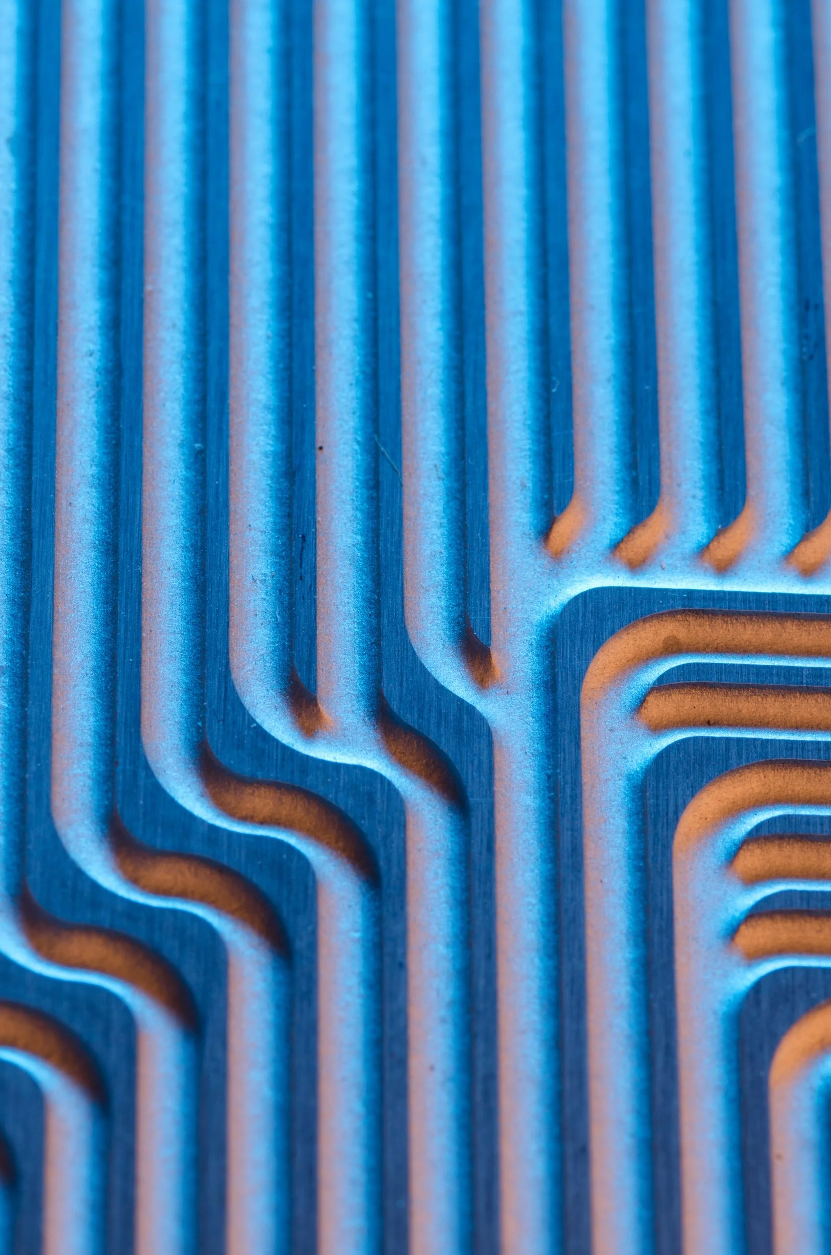 Close-up of a metallic heat sink with blue and orange lighting, showing parallel fins and a corner cutout.