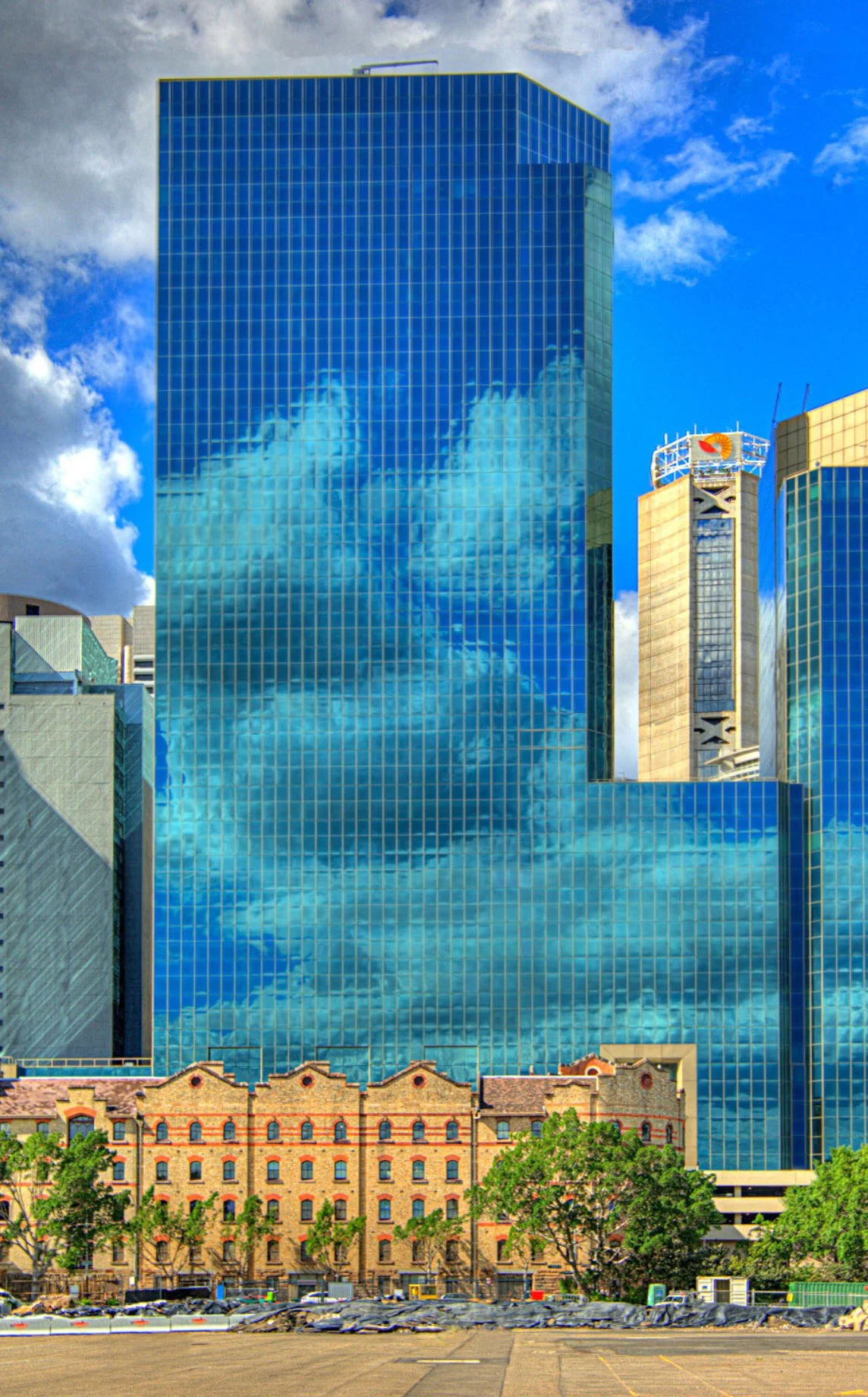 Reflection of clouds in the glass windows of a tall modern skyscraper in an urban cityscape.