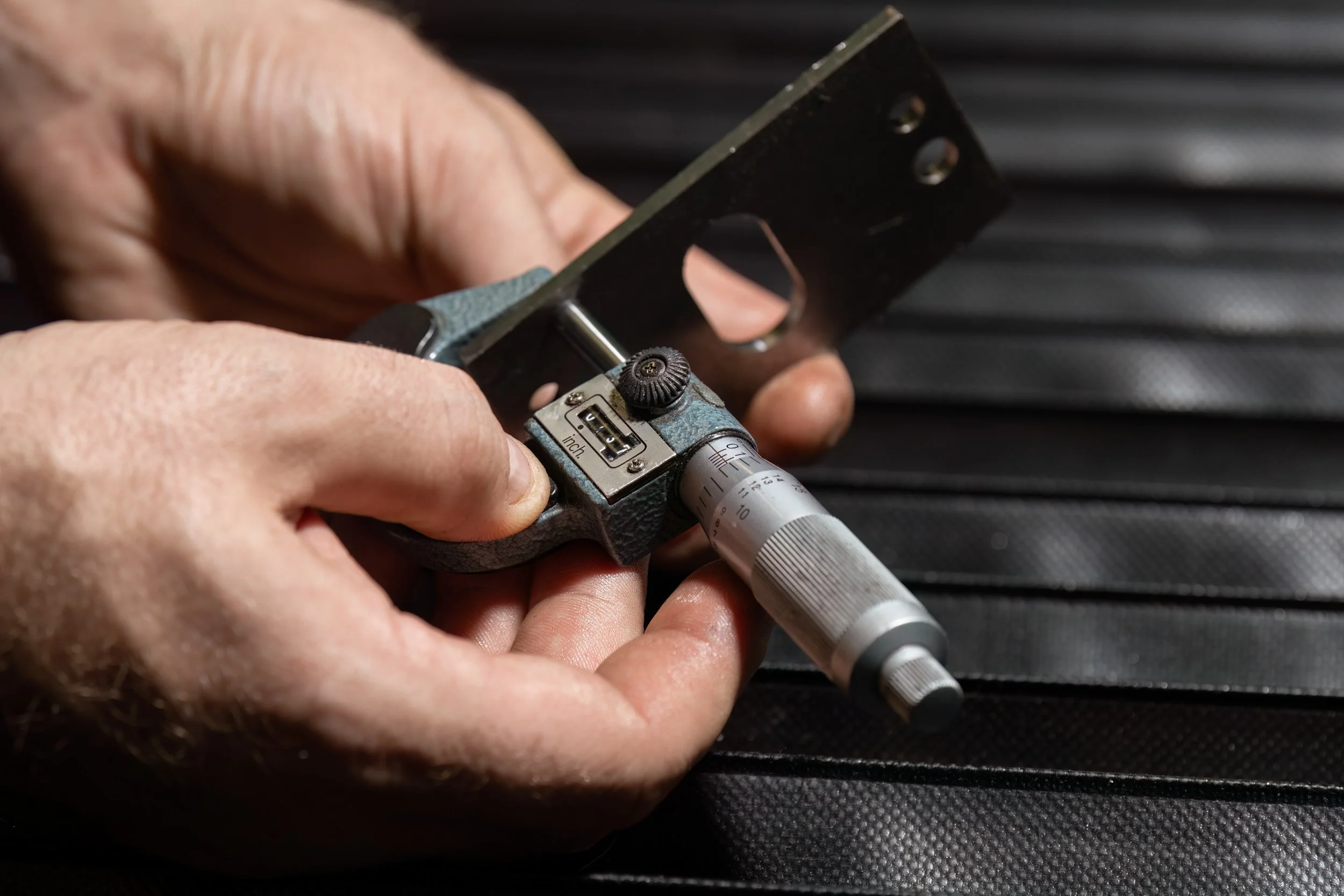 Hands with micrometer testing thickness of metal part