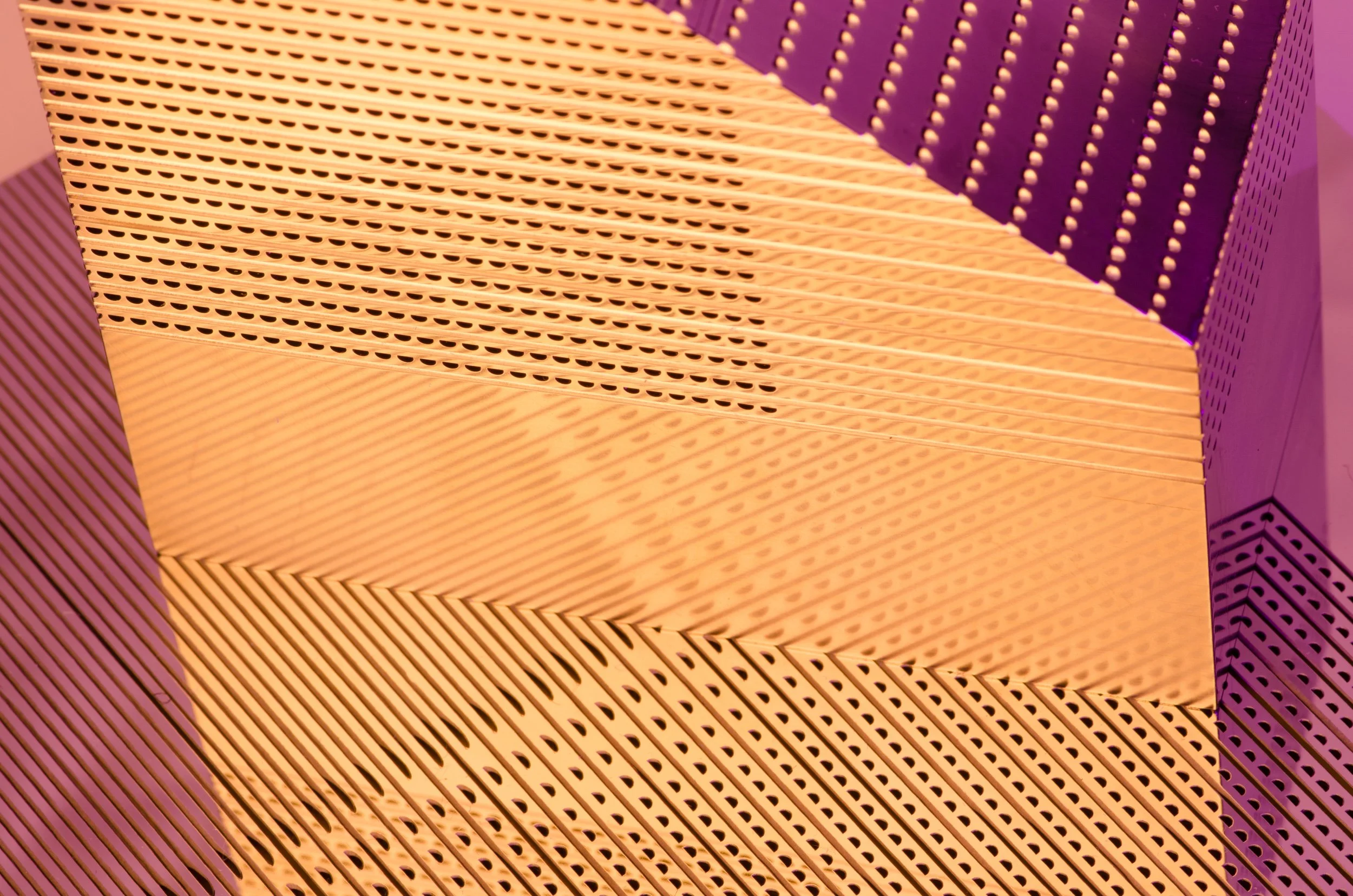 Close-up of geometric, perforated patterned panels, with beige and purple sections, creating an abstract architectural design.