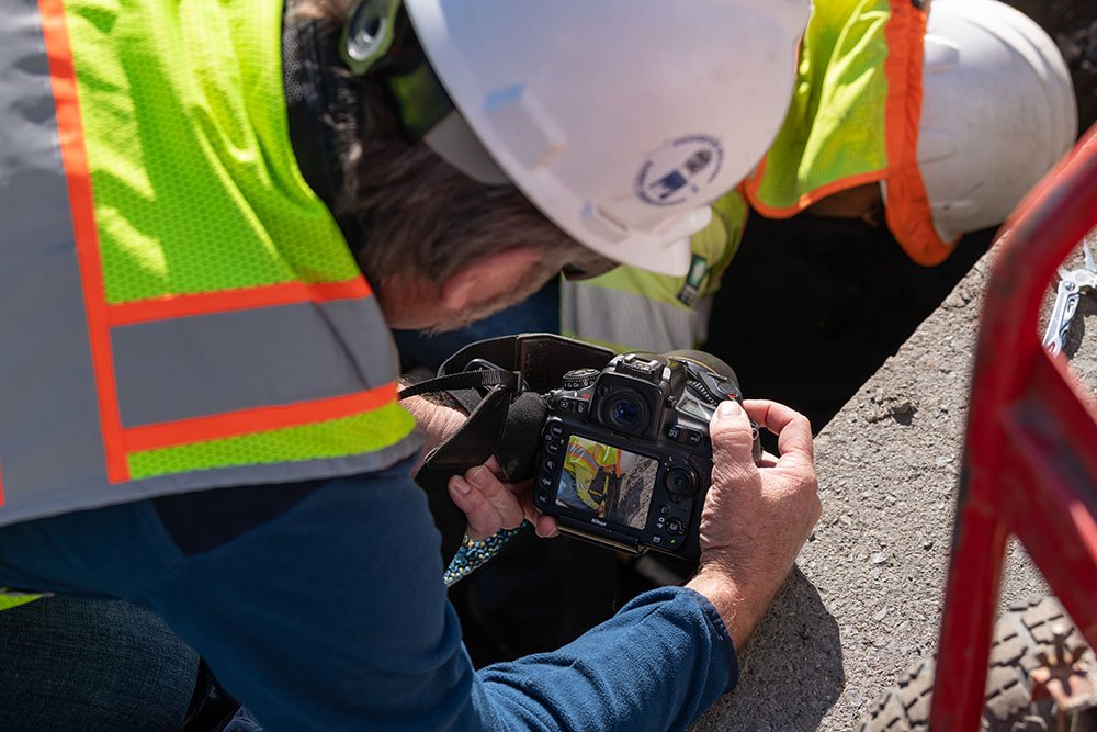 Duane on his knees shooting underground utility jobsite