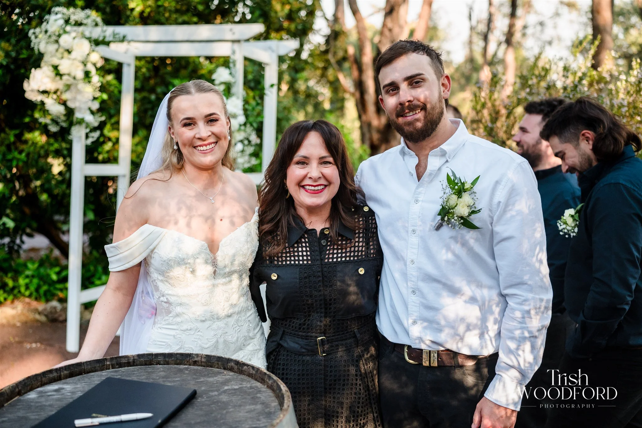 A bride and groom on the beach, smiling and touching foreheads.