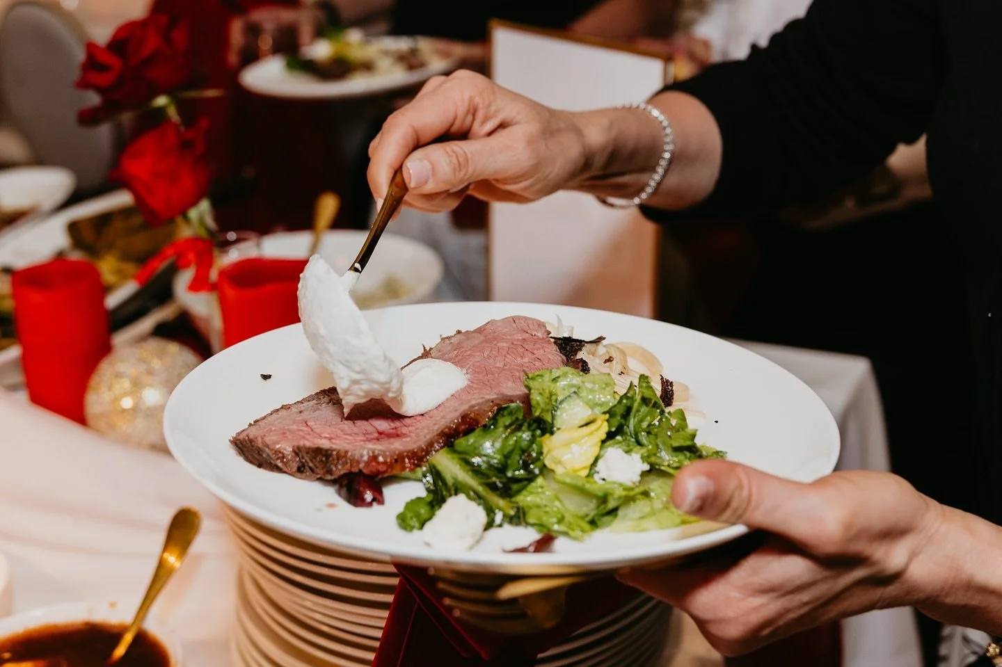 Guests enjoying every moment of our signature live carving station, featuring hand-sliced ribeye paired with freshly prepared greens, rich seasonal sides, and a selection of house-made sauces&mdash;including our creamy horseradish, crafted to complem