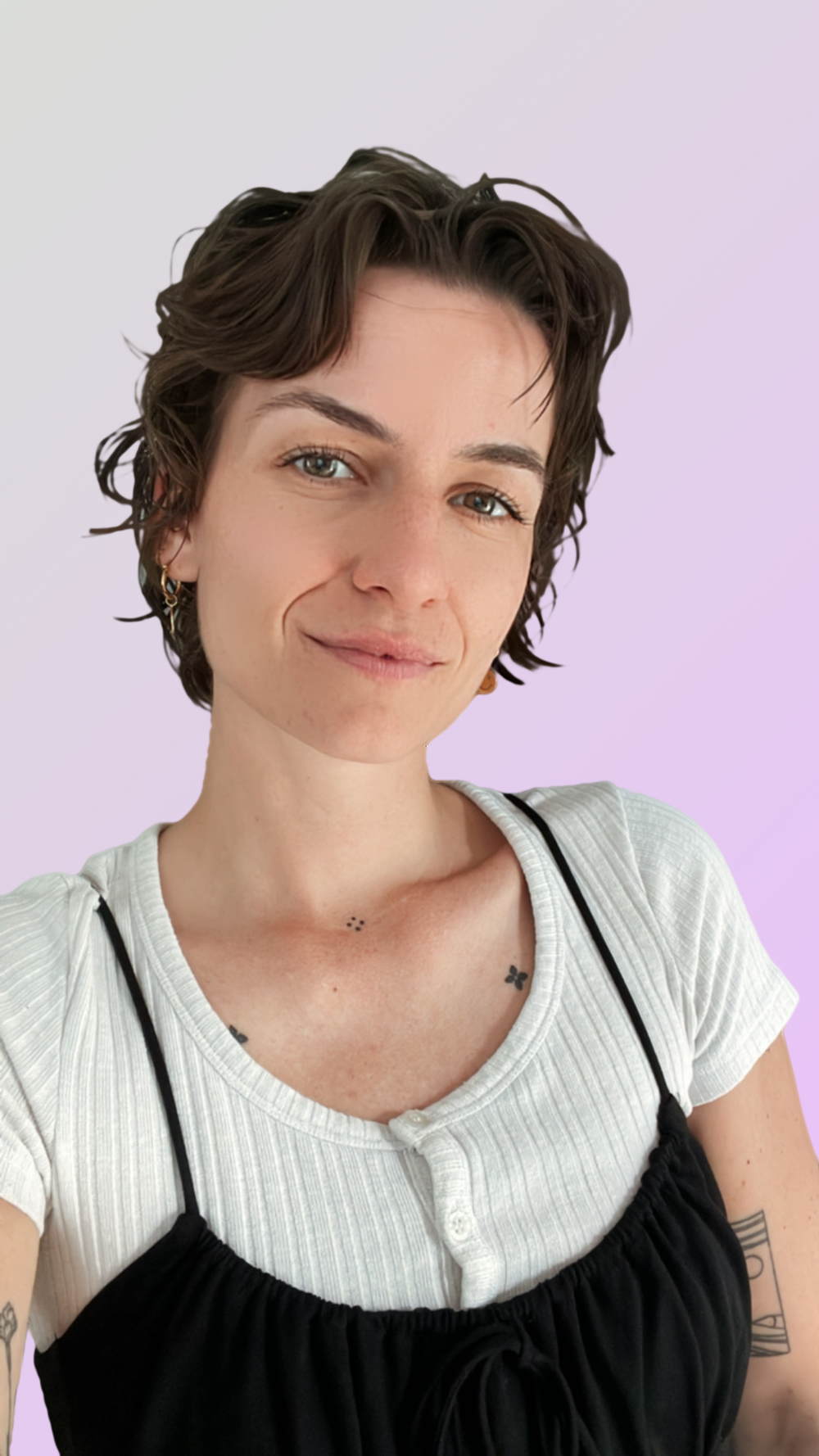 Junge Frau mit kurzen braunen Haaren, blauer Augen, dazwischen verschiedene Tattoos auf Arm, Baby- und Klee-Tattoo auf Hals, trägt weißen T-Shirt und schwarzes Kleid, lächelt leicht, helles lila Hintergrund.