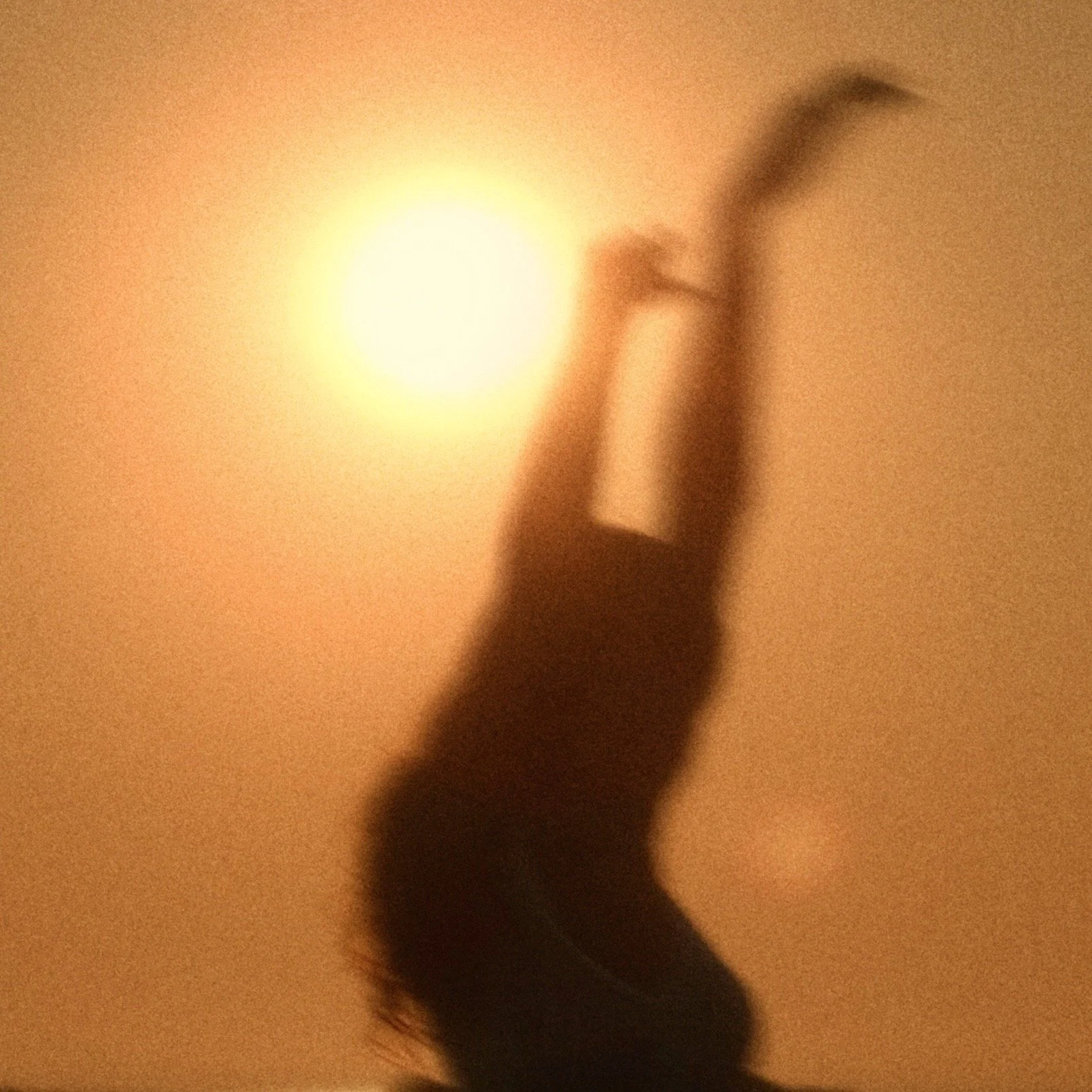 Shadow of a person with a raised arm reaching toward a bright circular light source, creating a silhouette against a warm, orange background.