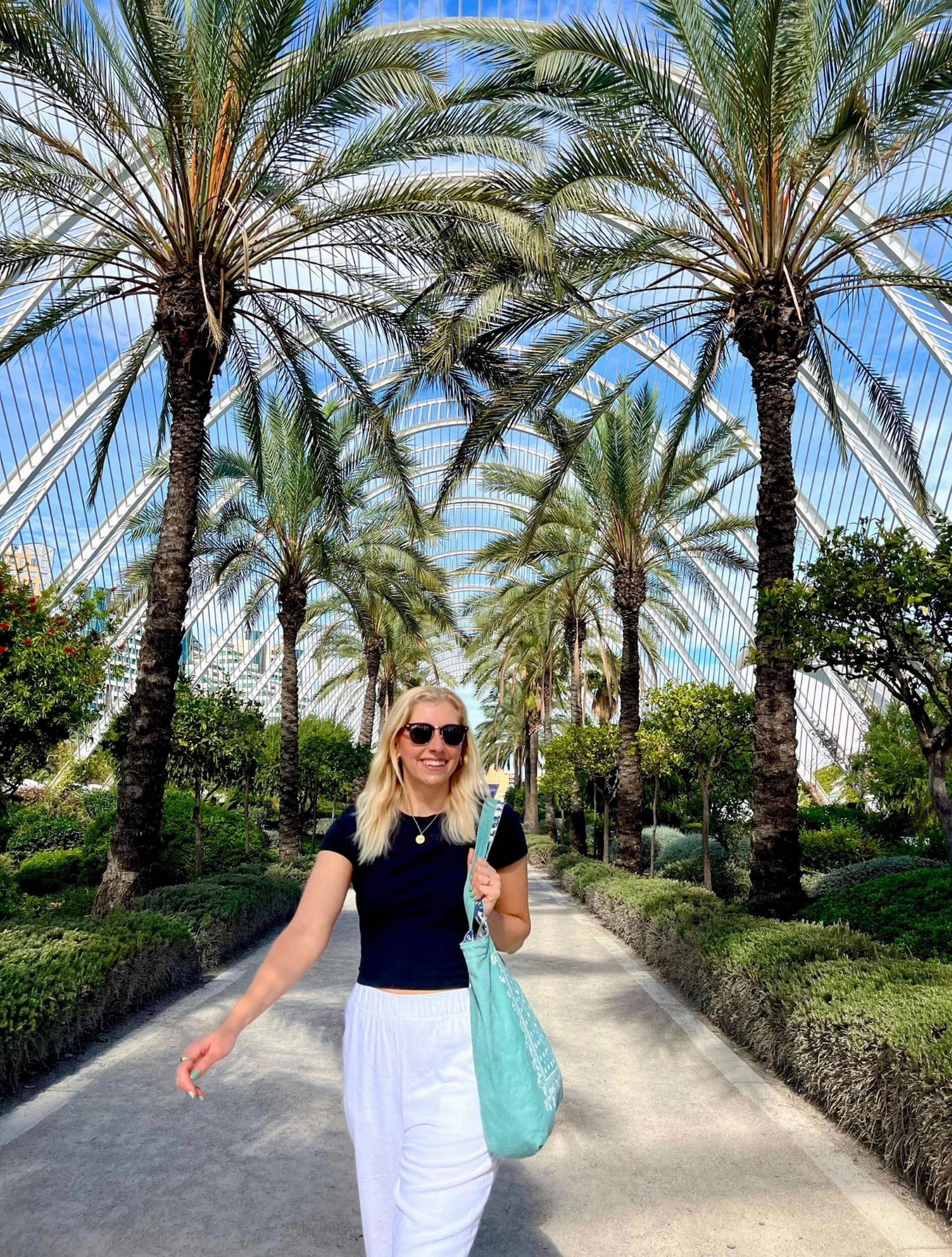 Woman walking in a garden with palm trees and a glass canopy