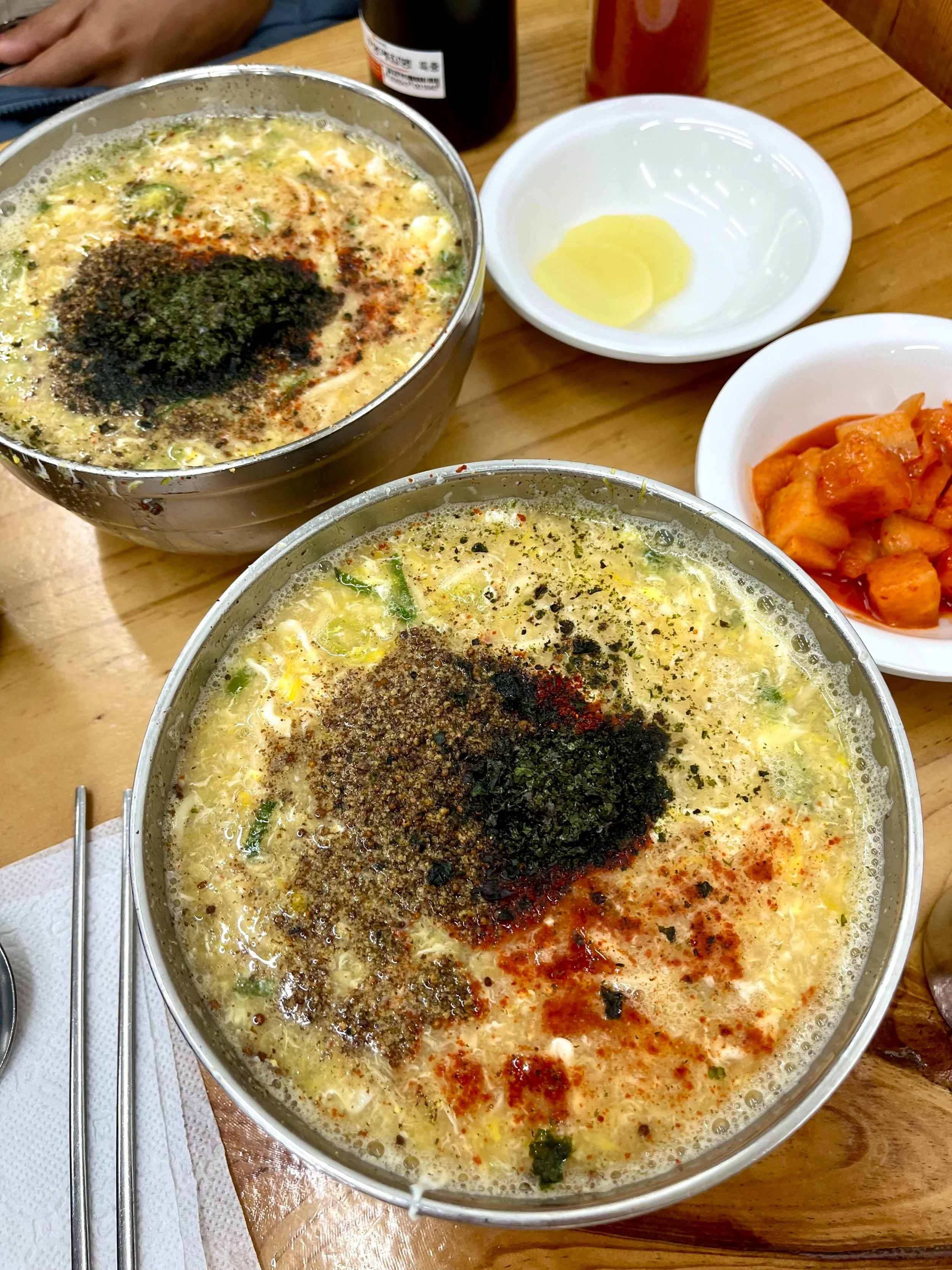 Two bowls of warm Korean noodles topped with seaweed