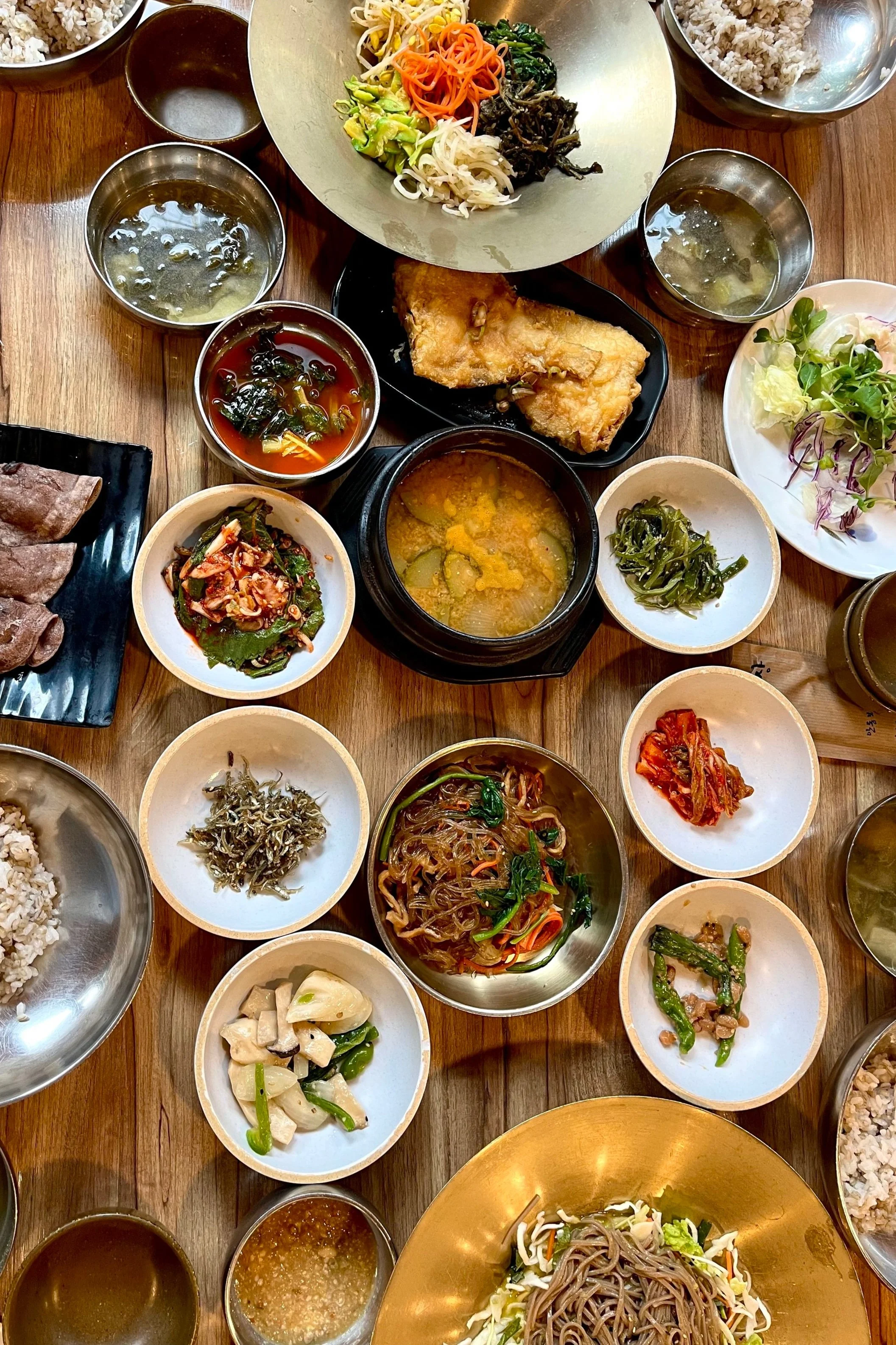 Table with Korean Food in multiple small bowls.