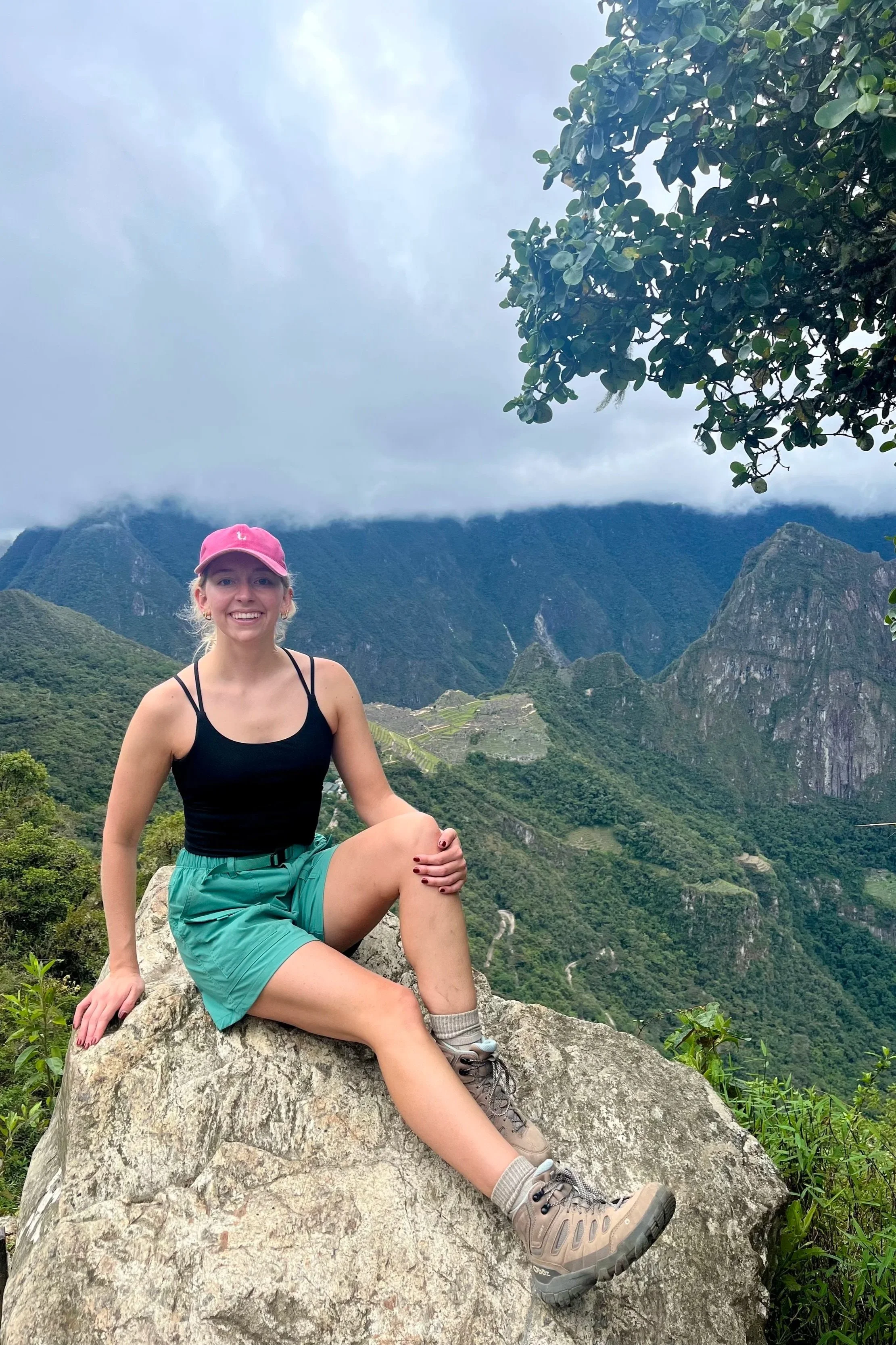Woman sitting on rock at the Sun Gate on the Inca Trail with Machu Picchu in background