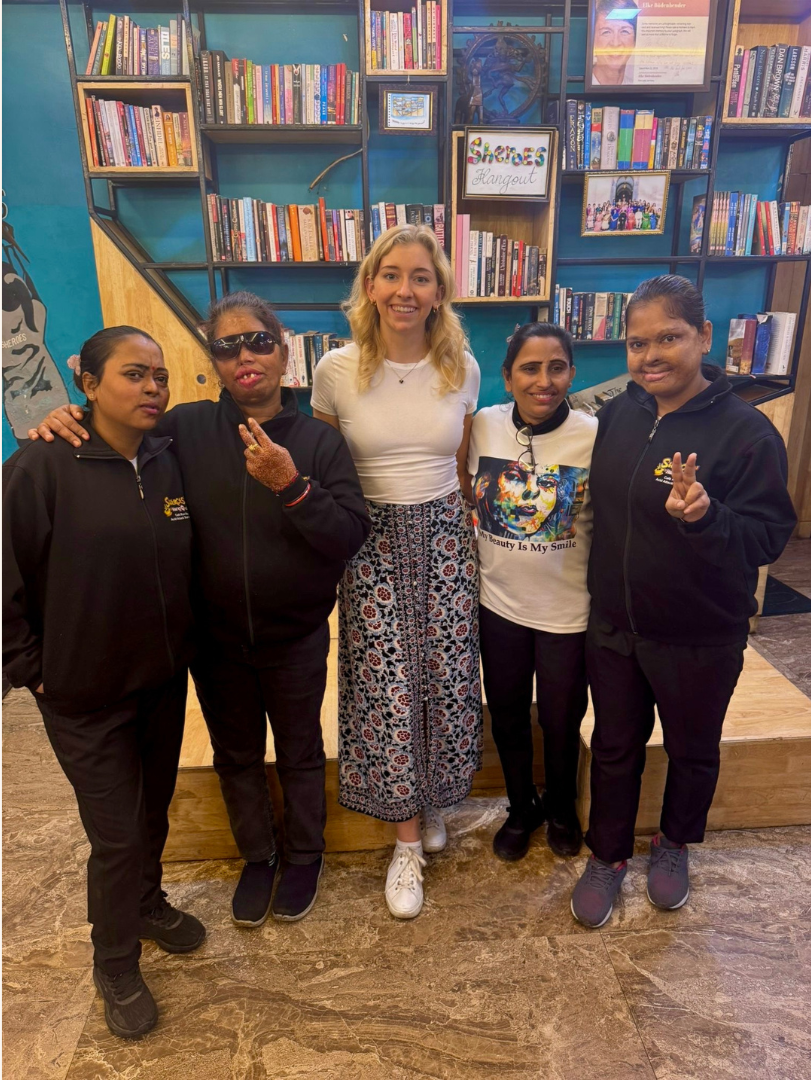 Blonde woman standing with four of the Sheroes Hangout acid attack survivor women in Agra, India