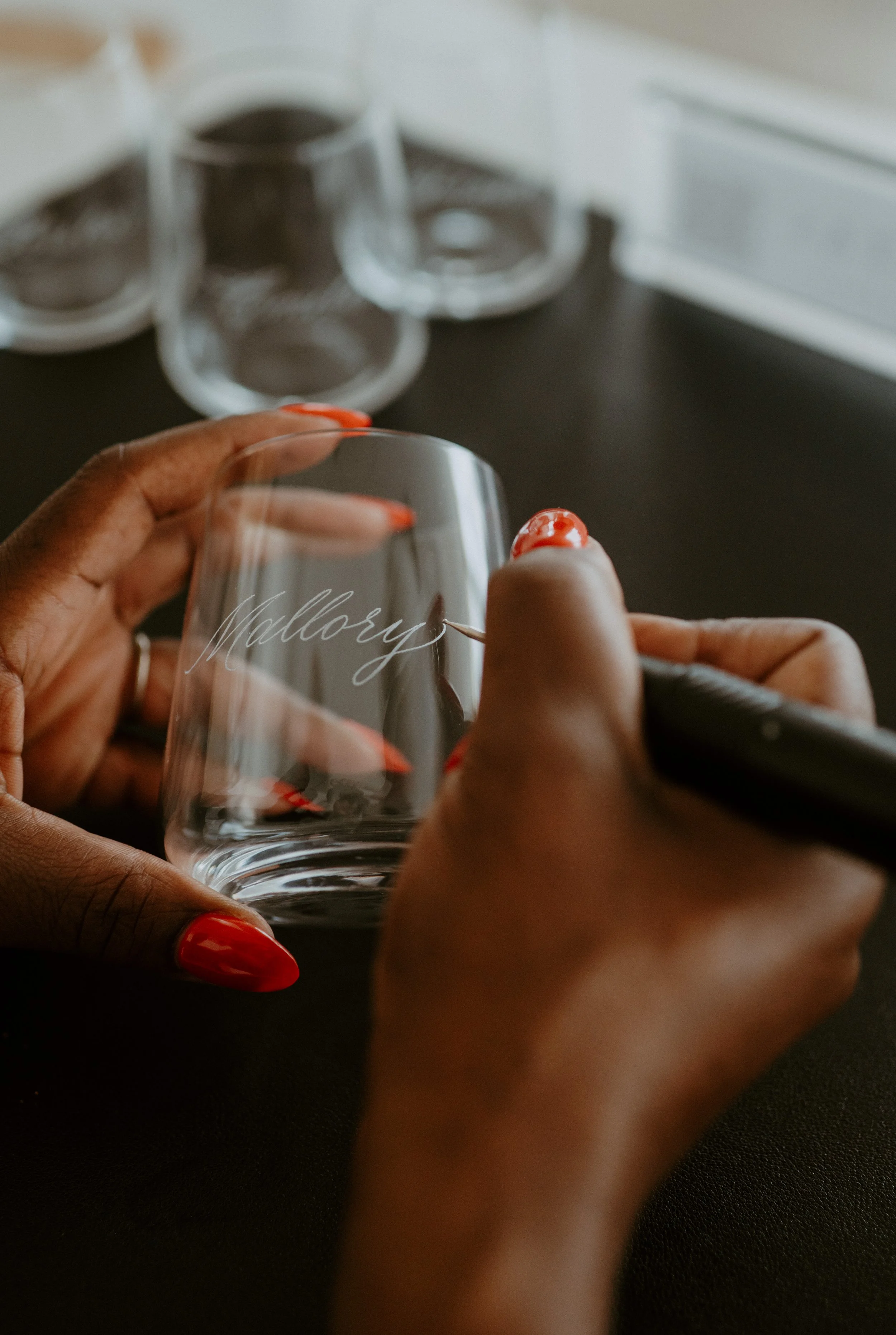 Close-up of hand engraving a guest's name onto glassware during a live event