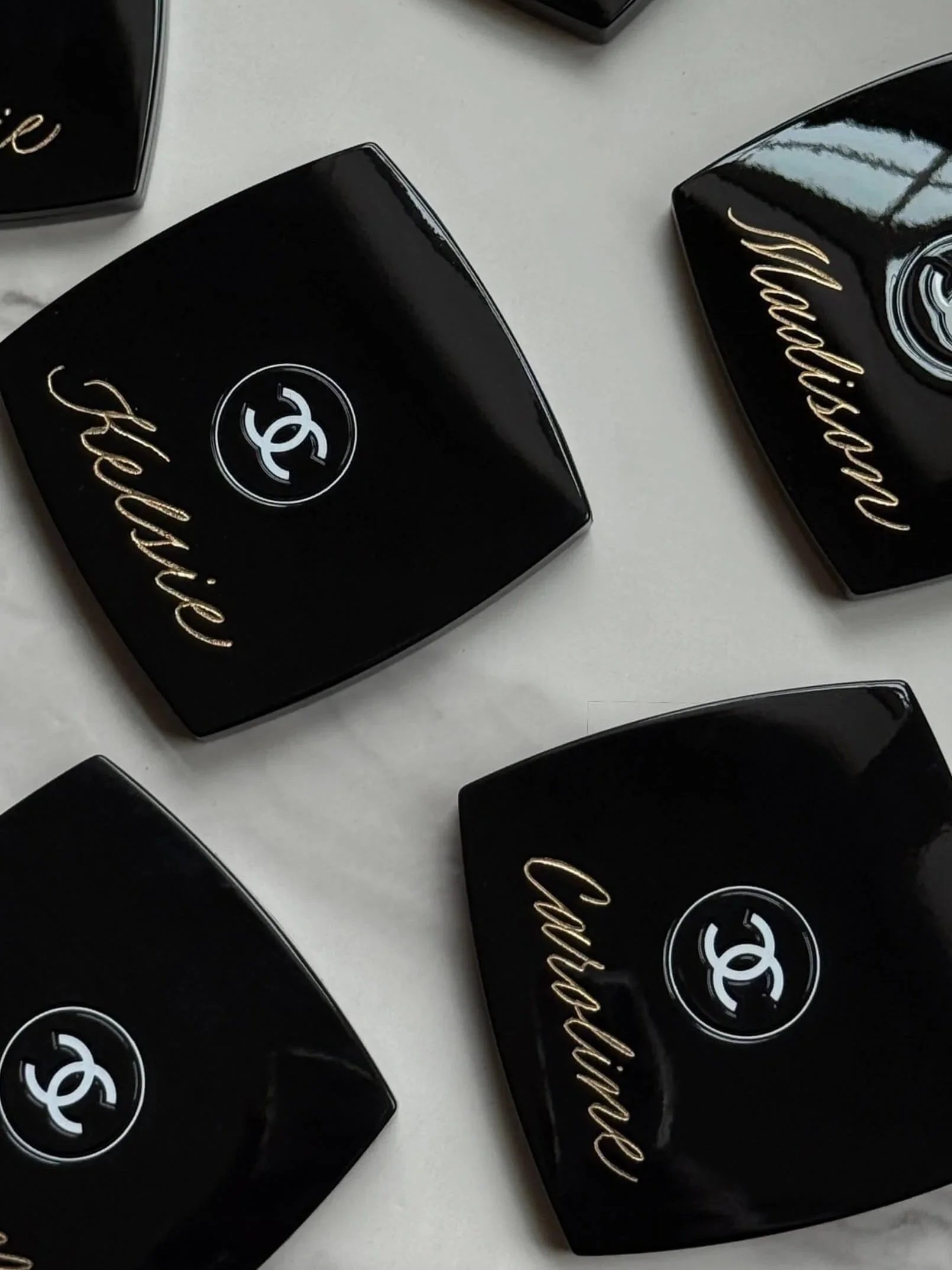 Custom engraved Chanel compact mirrors, inscribed with bridesmaid's names in gold lettering.