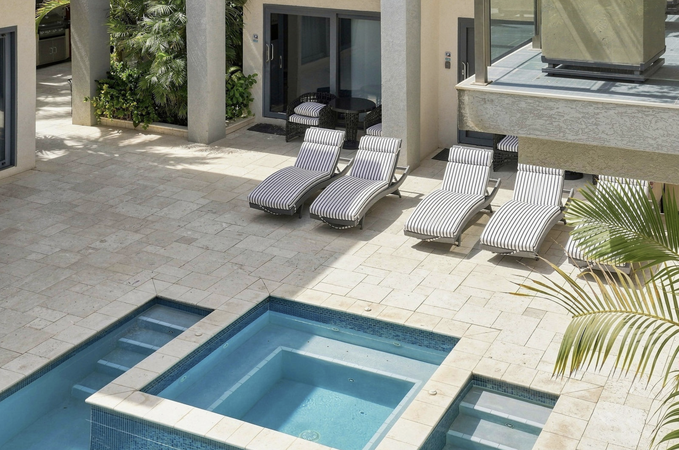 Poolside area with lounge chairs, outdoor seating, and lush greenery.