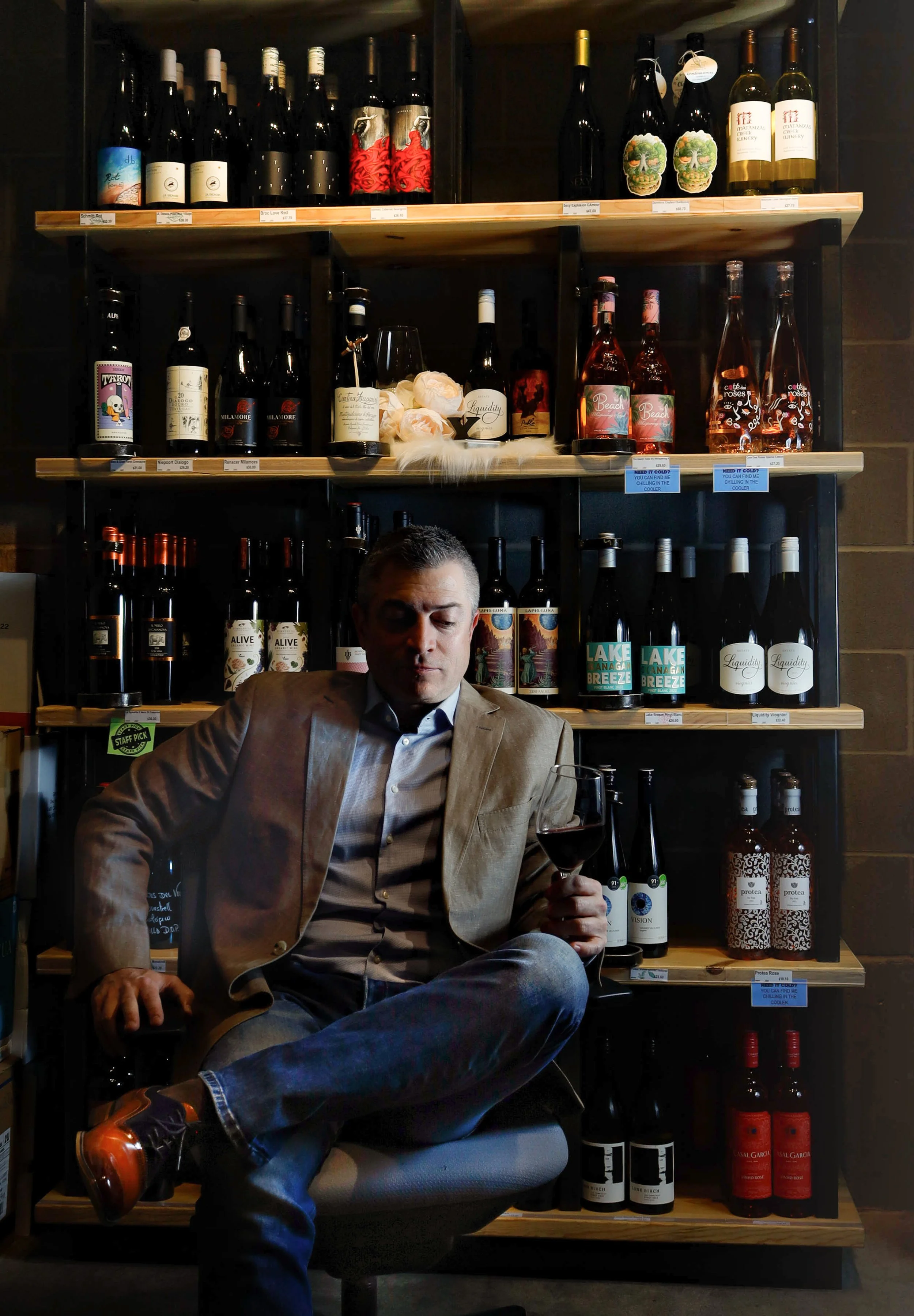 Editorial environmental portrait of a professional sommelier in a modern Calgary wine cellar, captured by Shifting Focus.