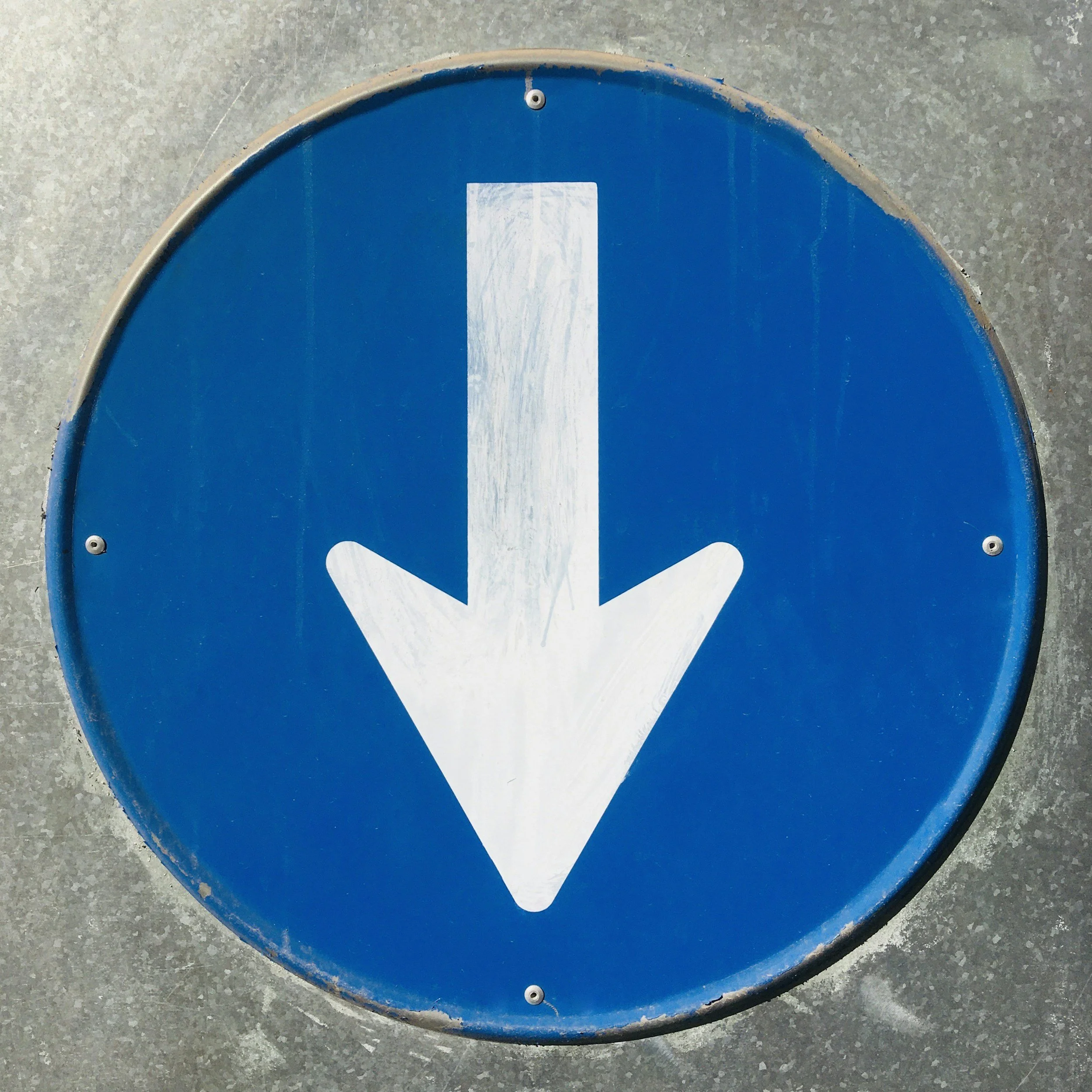 Blue circular traffic sign with a white downward arrow.